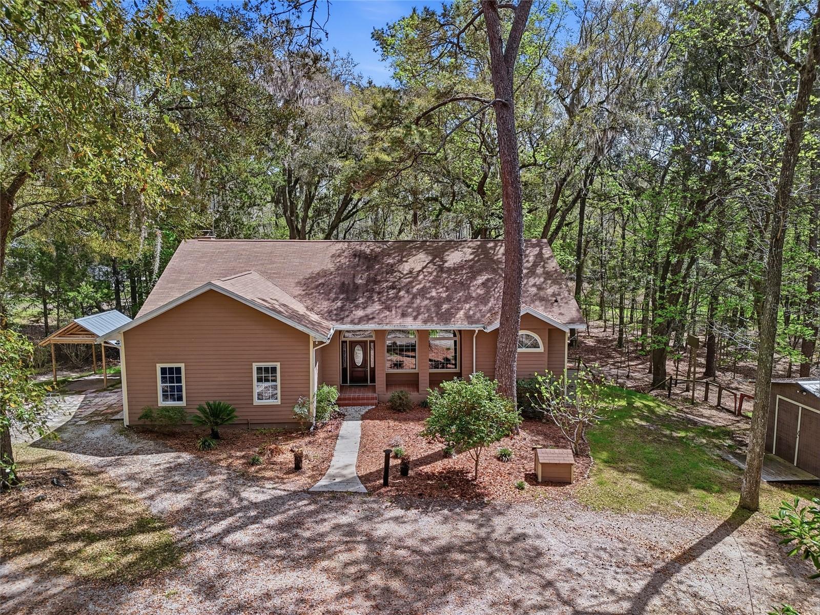 Welcome to this charming 3-bedroom, 2-bath home located in the desirable Bellamy Road Estates, situated off one of the most beautiful roads in the area. From the moment you arrive, the adorable front porch invites you to slow down and enjoy the peaceful surroundings. Step inside to find a bright and welcoming interior filled with natural light, high ceilings, and a thoughtfully designed layout. The home features a formal dining area and spacious living room, creating an ideal setting for both everyday living and entertaining. The massive kitchen is truly the heart of the home, offering abundant storage, a large island with bar stool seating, and a cozy eat-in area. It opens seamlessly to the main living room where a warm fireplace creates the perfect gathering space. French doors lead out to a spacious back porch overlooking the serene backyard—an ideal place to relax and enjoy the peaceful view of mature trees and nature. The primary suite is a private retreat featuring a beautiful bathroom with two large vanities offering ample storage and a spacious shower with dual shower heads. All bedrooms are generously sized, providing comfort and flexibility. The laundry room includes built-in shelving for added organization. Throughout the home, you’ll find durable luxury vinyl plank flooring with no carpet, making maintenance easy. Outside, the property is fully fenced and full of charm. Two sheds provide plenty of room for storage, hobbies, or outdoor toys, and there is even a chicken coop ready for your homesteading dreams. Enjoy fresh fruit right from your yard with producing grapefruit, lemon, and orange trees. This peaceful property offers privacy and mature landscaping while still being incredibly convenient. Located just seconds from I-75 and minutes to downtown High Springs and Alachua, local campgrounds, the Santa Fe River, and the area’s famous natural springs. Gainesville and Lake City are also just a short drive away, giving you easy access to shopping, dining, and medical facilities.