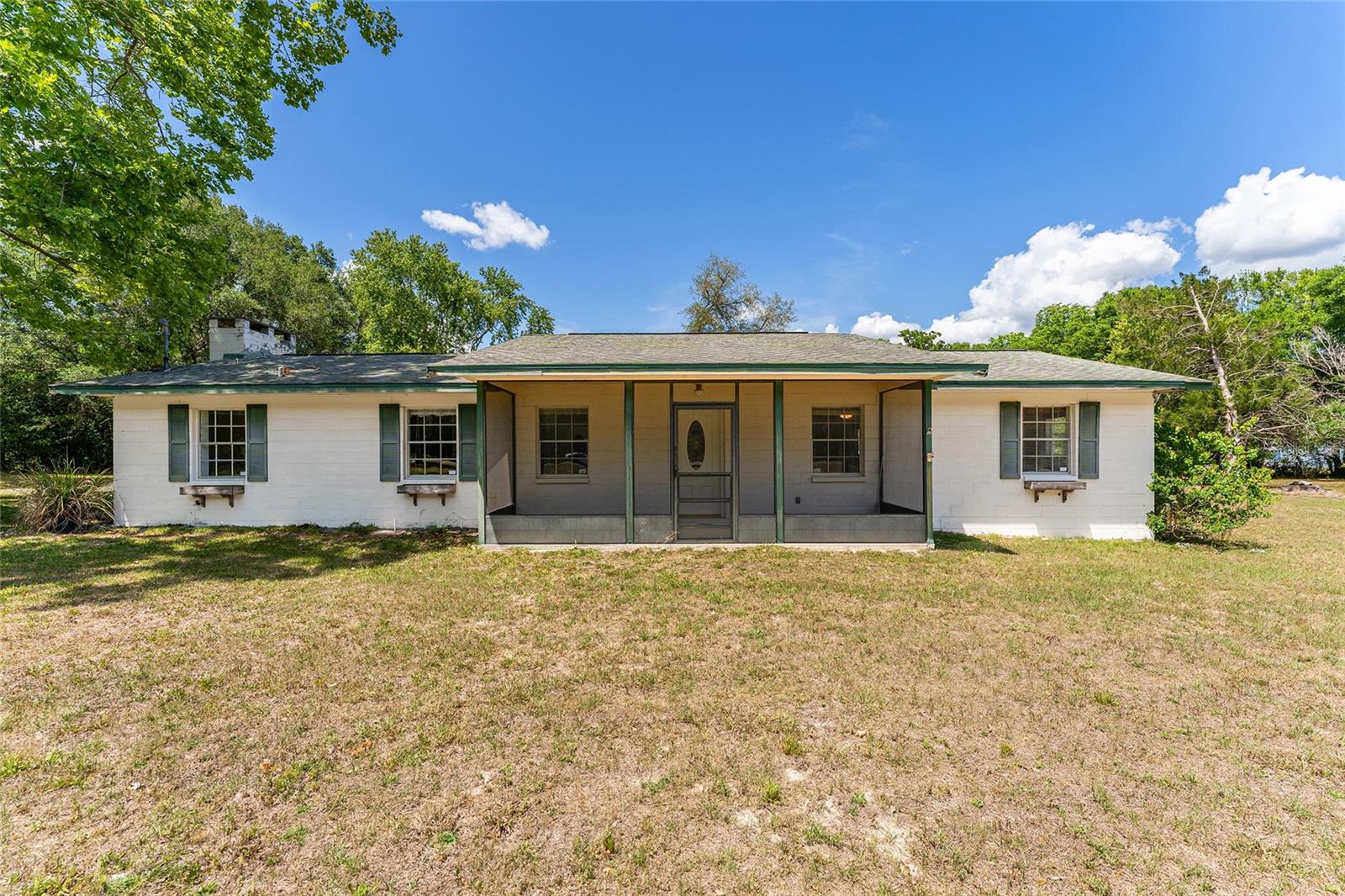 One or more photo(s) has been virtually staged. Located just outside of historic downtown High Springs, this solid concrete block 3-bedroom, 3-bath home offers nearly 1,900 square feet of conditioned living space. Set on 4.23 acres, the property presents endless possibilities, perfect for gardening, recreation, or simply enjoying a peaceful, private setting. Inside, a spacious living room welcomes you in, with easy flow to the kitchen and dining areas. A separate family room, anchored by a cozy wood-burning fireplace, provides the perfect gathering space for cooler evenings and relaxed nights at home. The dedicated dining room connects seamlessly to the kitchen, creating an inviting layout for both everyday living and entertaining. The primary bedroom offers an ensuite bath with walk-in shower. The two guest bedrooms are equally spacious and share the third full bathroom. 
One of the home’s standout features is the oversized laundry room equipped with washer, dryer and a full bath, ideal for work/hobby space. Step outside and take in the wide-open acreage and expansive skies. Just two miles from O'Leno State Park offering access to over 6,000 acres of swimming, kayaking, fishing and hiking along the scenic Santa Fe River and minutes to local shops and restaurants in historic downtown High Springs.
