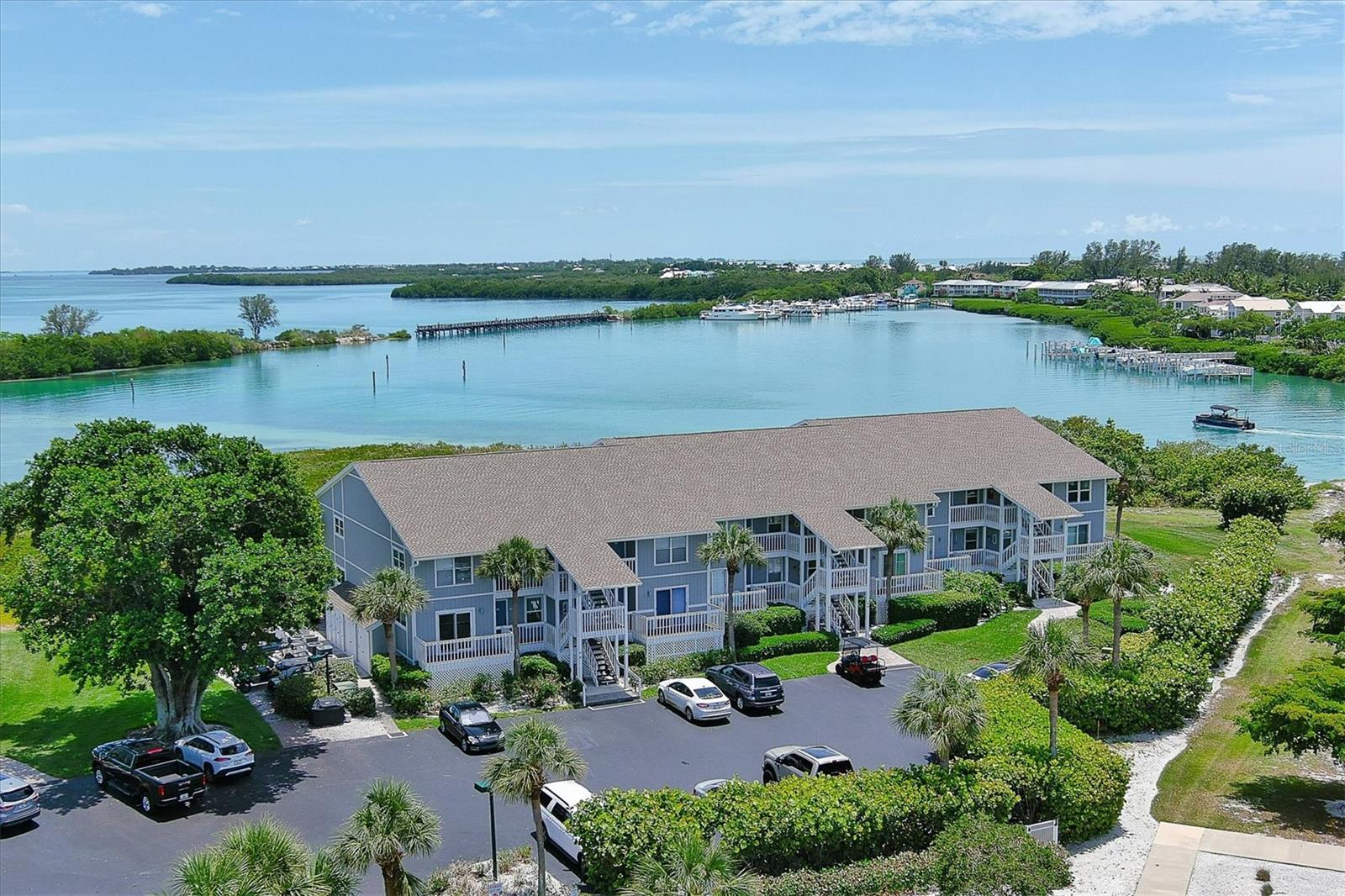 Experience the ultimate island lifestyle in this beautifully furnished and fully updated 2-bedroom, 2-bath coastal retreat—complete with private deeded boat slip #4 featuring a 13K lift with electric and water. Thoughtfully designed with both comfort and sophistication in mind, with stunning views of the Gasparilla Sound and partial views of the Gulf.  Whether you are looking for your own private residence or investment property - this unit can be either or both.  The gorgeous Boca Grande North gated community leads you beautifully onto Gasparilla Island and has been fully updated and renovated.  
Step inside this home featuring a bright and airy open-concept living space, where natural light pours through expansive sliding doors and highlights the home’s stylish finishes. The updated kitchen offers cabinetry lighting, generous counter space and flows into the spacious dining and living areas—perfect for relaxed evenings or hosting friends after a day on the water. The expanded Florida room invites you to enjoy morning coffee, island breezes, or vibrant sunset views overlooking tranquil waters and lush tropical surroundings.  This property was taken down to the studs with all-new electrical, premium materials and living spaces redesigned.

Both bedrooms provide peaceful sanctuaries, each with its own set of sliding glass doors that open to private decking—ideal for stepping outside to enjoy the quiet morning air or unwinding beneath the stars. The primary suite is exceptionally appointed with ample closet space, an in-unit laundry area for added convenience, and a beautifully en-suite bath featuring double sinks and a spacious walk-in shower. The guest bedroom is equally welcoming, with easy access to its own private outdoor space.   The beautifully upgraded guest bath offers a walk-in shower.  Have furry friends? As an owner, you can bring them too!

Beyond the residence itself, the community offers an impressive array of amenities designed to enhance every aspect of island living. Enjoy a refreshing dip in the heated pool, relax in the hot tub, or gather with friends at the clubhouse. Stay active with tennis and pickleball courts, a well-equipped fitness center, and lighted walking paths that wind through the property’s gorgeous tropical landscaping. Additional conveniences include a golf cart charging station, BBQ grills for easy outdoor dining, and serene common areas perfect for relaxing after a day of island exploration. This unit features an outdoor storage closet and access to dockage.

With your own boat slip just steps away, world-class boating, fishing, kayaking, and Gulf adventures are effortlessly accessible. Located along the Boca Grande Causeway, this condo provides quick access to boutique shopping, waterfront dining, pristine beaches, and the charming village of Boca Grande.  The Boat Slip is deeded, dock is with composite material, and you do not need to be a Boca Grande North condominium owner to purchase - makes for a great investment if you want to later sell separately! Deepwater with no bridges and only minutes to the ICW and Gulf!
Whether you're seeking a worry-free vacation home or a full-time island retreat, this residence embodies the carefree, sun-soaked lifestyle that only Boca Grande can offer—your personal slice of paradise awaits.  6000 Boca Grande Causeway, Unit D40
Community buildings feature new roofs, siding, impact windows, spray insulation, and other upgrades.