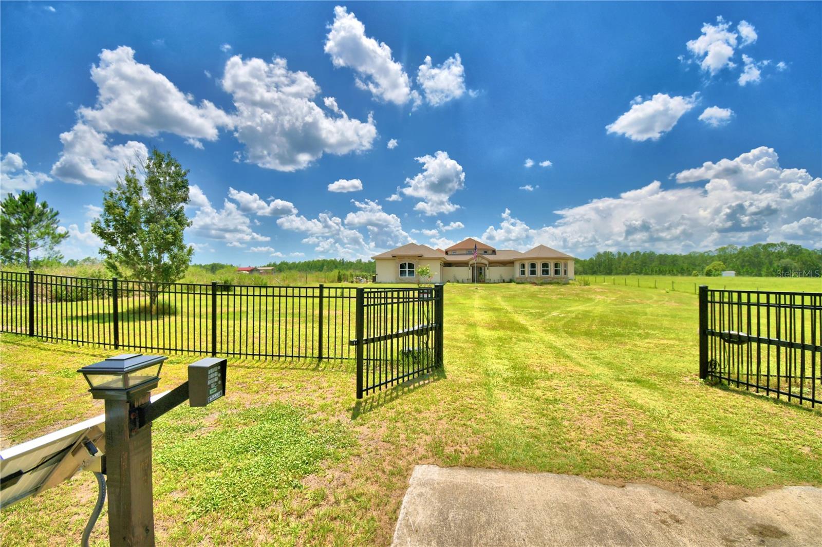 Welcome to country living at the executive level. This extraordinary custom estate offers privacy, security, and one-of-a-kind design with no HOA restrictions and no community regulations. Enjoy the freedom to store your RV, boat, trailers, recreational vehicles, and other toys or farm animals without the limitations often found in deed-restricted communities. Situated on nearly an acre of land, this impressive property is conveniently located just across the street from Second Star Farms and only minutes from world-famous attractions, shopping, dining, and entertainment. As you arrive, you'll be greeted by a gated entrance and a first glimpse of this expansive estate. A second gate leads to a stunning enclosed courtyard featuring custom Mickey-inspired wrought iron gates. The home's unique exterior architecture subtly incorporates the iconic shape of Mickey Mouse, creating a truly distinctive property unlike any other. From the private courtyard, you'll find access to a detached in-law suite, offering flexible living arrangements for extended family, guests, caregivers, or even a private home office. Step inside and immediately notice the soaring tower ceilings, enormous decorative columns, and expansive living spaces that set the stage for elegant living and entertaining. The open-concept design flows seamlessly into the gourmet kitchen, where no expense was spared. Features include top-of-the-line Bosch appliances, a wine cooler, custom cabinetry, granite countertops, and abundant workspace for preparing meals and gathering with family and friends. The thoughtfully designed split floor plan in the primary residence includes three spacious bedrooms and three bathrooms, providing comfort and privacy for family members and guests alike. Combined with the detached in-law suite, the property offers a total of four bedrooms and four bathrooms. Just off the kitchen, the laundry room is conveniently located near the secondary bedrooms and includes an exterior access door. This smart home is equipped with features rarely found in today's market, including an electronic doggie door that opens exclusively for your pet, preventing unwanted animals and critters from entering the home. Additional smart features include an Ecobee Smart A/C system for enhanced comfort and energy efficiency. Located on the opposite side of the home, the oversized primary suite serves as a private retreat. This luxurious space features an enormous walk-in closet and a spa-like ensuite bathroom complete with a soaking tub positioned center stage for ultimate relaxation. Prepared for virtually any situation, this property also includes a secure safe room, providing peace of mind during severe weather, emergencies, or unexpected events. Combining luxury, innovation, security, and country charm, this remarkable estate offers a lifestyle that is truly second to none.
