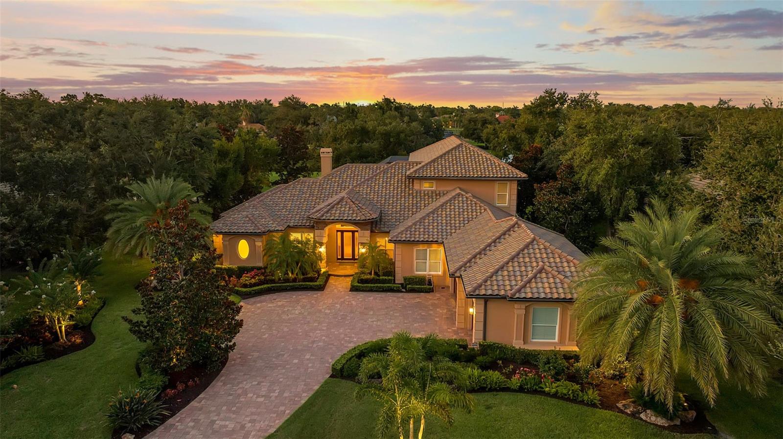 Welcome to your dream home, a sanctuary of elegance and comfort nestled on an exclusive, private street with only nine residences and no neighbors across the way—just the tranquility of a natural preserve. This remarkable property in The Oaks Clubside, with 4 bedrooms, 5 full bathrooms, and 2 half baths, boasts impact windows and doors throughout, providing peace of mind and a quiet, secure environment. Step inside to discover an open floor plan adorned with a blend of rich wood and luxurious travertine floors. Each of the large bedrooms is an en suite retreat, offering privacy and comfort for residents and guests alike. On the first floor you will find a huge master suite, with his-and-her closets, and a luxurious master bathroom that has two separate vanities, a walk-in shower and soaking tub.  The two additional bedrooms are generously sized. The open kitchen features cherry wood cabinets, a granite island and high end stainless steel appliances. The breakfast nook is flooded with natural light and offers a lovely view over the pool. The second story has a fourth en-suite bedroom, and balcony overlooking the golf course and lake. And, for those who love to entertain, the game and media room is designed for fun gatherings of friends. The heart of the home extends outdoors, where you will find an impressive outdoor kitchen area  perfect for grilling and dining alfresco. Enjoy a beautiful, long view of the Heron #14 and the serene lake beyond—a panoramic scene that will take your breath away every day. This home is loaded with thoughtful additions, including three new exterior ceiling fans for comfort on warm days, custom office closet shelving and a secure dog run fence for your furry friends. The garage boasts a durable epoxy floor and hurricane-rated doors. Additional upgrades abound with 4 new AC units with UV lights for optimal air quality, a new roof, two-stage pool pump and new irrigation pump, new tankless Navian water heater to name a few.  You absolutely must see this home to appreciate all it has to offer. Membership in The Oaks Club, Sarasota’s premier golf and country club is required with home ownership.