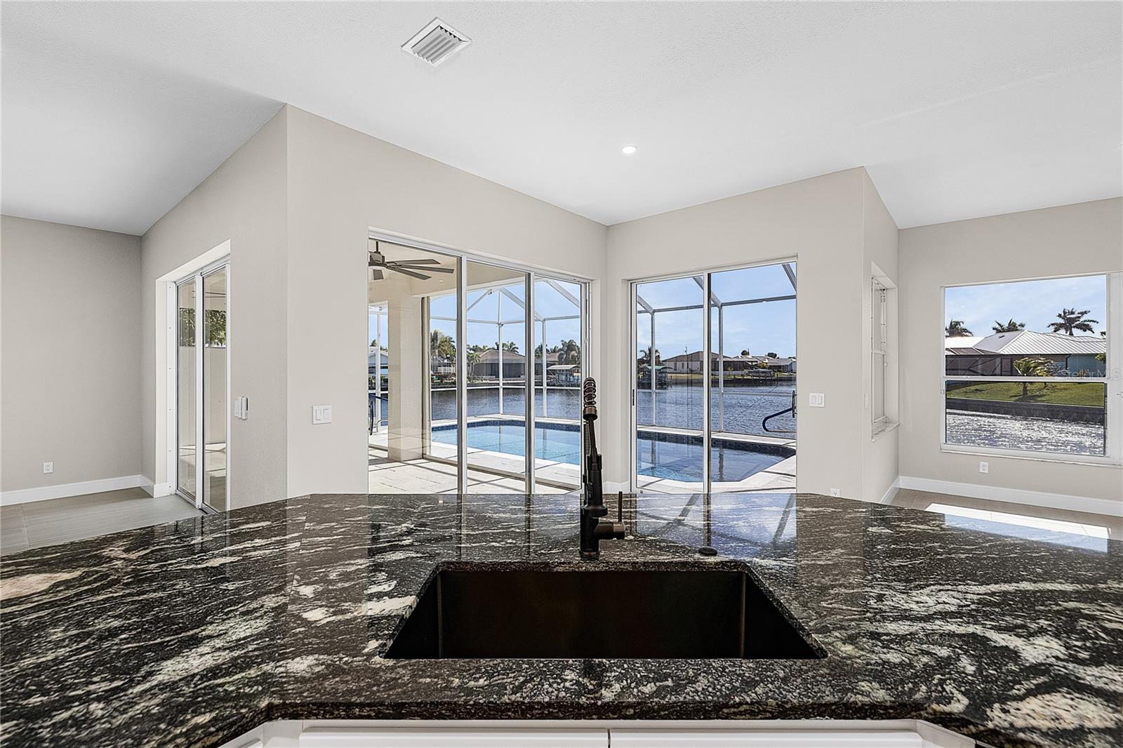Extensively newly remodeled GULF ACCESS WATERFRONT home offers a rare blend of modern design, thoughtful upgrades, and lifestyle flexibility that stands apart from today’s repetitive new construction typical floor plans you see over and over. Featuring 3 bedrooms with one of the guest bedrooms drastically oversized, 2 bathrooms, a separate living and family room layout, and a 2 car garage. This home is designed for both everyday comfort and entertaining without having to worry about remodeling because just about everything has been recently redone. The bright open kitchen showcases custom soft close cabinetry, level 3 granite countertops, a very large non-traditional center island, new BLACK STAINLESS STEEL LG appliance package with 36 inch GAS COOKTOP and wall microwave wall oven combo with an impressive WALK IN BUTLER’s PANTRY complete with GLASS BARN DOORS, wine cooler, abundant storage, and additional countertop space. Oversized 24x48 porcelain tile flooring everywhere, recessed LED lighting, and expansive windows create a light filled interior with seamless indoor outdoor waterfront flow. The family room is anchored by a designer shiplap feature wall with gas fireplace with a striking marble look surround to be a focal point of the main living area. Both bathrooms have been fully updated with custom cabinetry, granite counters, black matt shower systems, LED mirrors, and beautifully tiled showers, while the primary suite offers a spa like retreat with a large walk in closet and shower with luxury high end elegant finishes. Major system updates include a newer roof, brand new AC system, full home re pipe, and updated lighting throughout, with SO MUCH MORE providing peace of mind for years to come. Outdoors, enjoy an OVERSIZED WATERFRONT LOT with seawall approximately 145 feet of Gulf access water frontage, a short boat ride to open water with only one bridge, and a brand new fully resurfaced pebble tech like with glass tile and newly installed stone coping solar heated pool framed by a screened lanai and amazing waterfront views. Additional highlights include a remodeled front façade, impact rated entry door, hurricane shutters, new landscaping, and transferable LOW COST FLOOD INSURANCE (approx. $1030/year). Located in a city water and sewer neighborhood surrounded by newer high value homes and a short bike ride or walk to the popular 7 ISLANDS PROJECT and local parks. Embers Pkwy is currently undergoing a “median beautification” and will have lush landscaping as you come into your wonderful neighborhood. This property delivers the space, character, and upgrades buyers want without settling for another identical floor plan, making it an ideal full time residence or luxury seasonal retreat. Please ask to see the full “Upgraded Feature List”. Buy this unique one of a kind home now before someone else does!