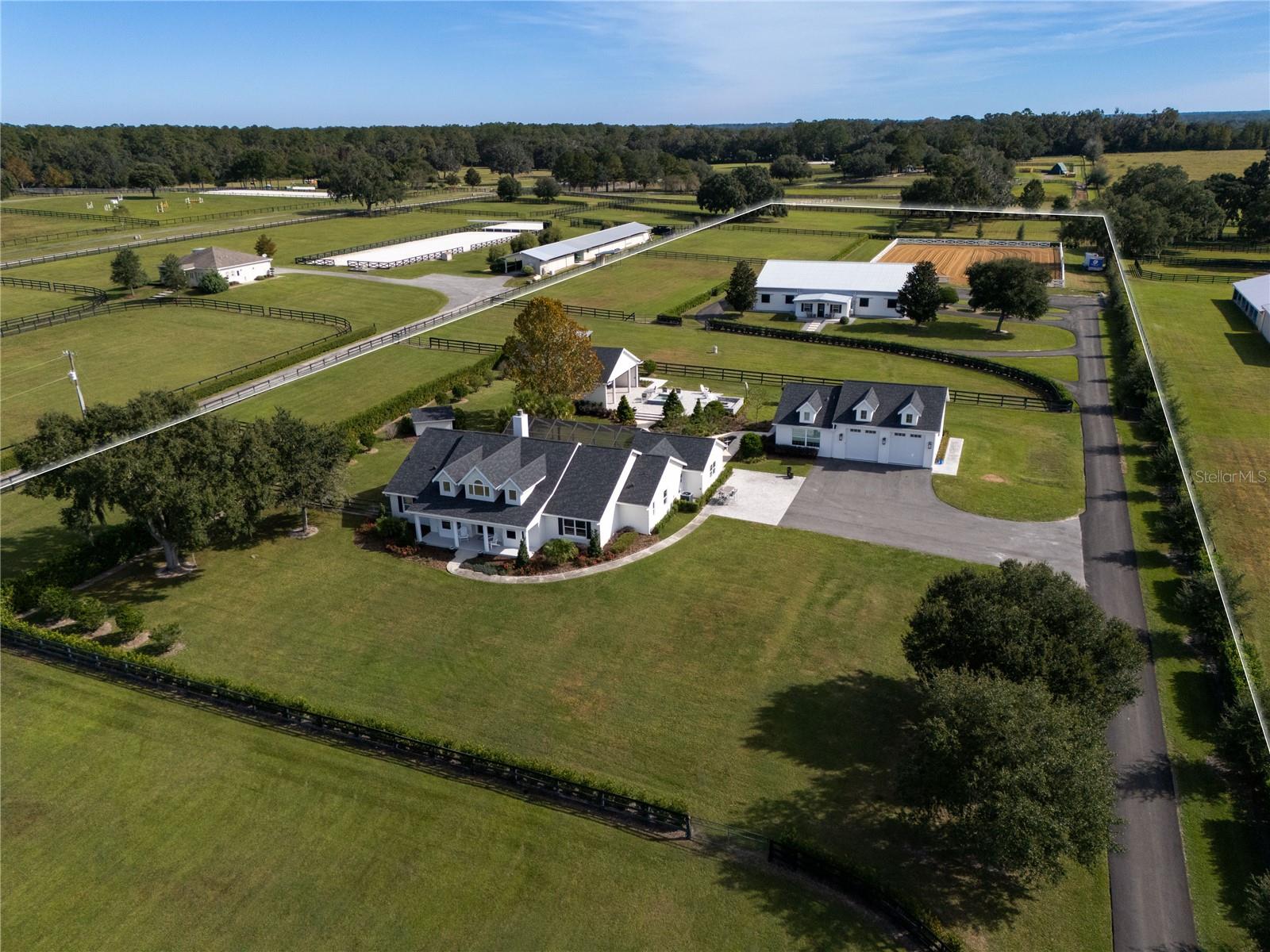 Just minutes from world-class equestrian venues, this 10-acre fully fenced estate offers versatility, charm, and exceptional convenience. Located 10 minutes to the World Equestrian Center and only 5 minutes to Golden Ocala, the property combines an ideal location with thoughtful design and extensive amenities for both homeowners and equestrians. A tree-lined driveway welcomes you onto the property and sets a beautiful tone as you approach the heart of the estate. Toward the back of the acreage sits a spacious 6-stall barn featuring rolling doors, washracks, a tack room, laundry room, bathroom and a comfortable apartment/office area. A separate barn kitchen is centrally located within the barn,ideal for convenience during long days on the property. There is also ample parking space for equipment. Just beyond the barn, riders will appreciate the clay-footing riding arena and surrounding paddocks. The main home offers an inviting layout with 4 bedrooms, 2 full baths, and 1 half bath, and an office. High ceilings and a centrally placed fireplace bring character and warmth to the living space, while select bedrooms feature soft carpeting for added comfort. The kitchen is complete with updated appliances, a butcher block island, and a charming breakfast nook that frames views of the pool. The back porch flows seamlessly to the screened-in saltwater pool, creating an elegant outdoor living space. Outside the pool enclosure, a paved walkway leads to a tranquil outdoor retreat that includes a spa, firepit, seating area, and a covered outdoor kitchen for gatherings and enjoying Florida’s beautiful weather. A small pool house provides convenient storage for outdoor and pool essentials. For added versatility, the property also includes a studio apartment within the garage, complete with a full kitchen,full bathroom, and laundry area, an excellent option for guests, staff, or rental income. Move-in ready and thoughtfully outfitted for equestrian living, this property blends comfort, convenience, and rural elegance in one of Ocala’s most desirable locations.