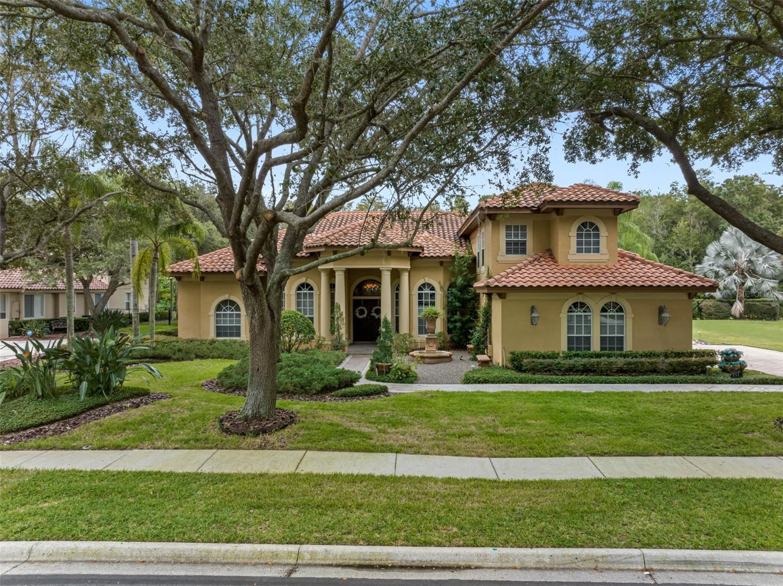 Designer Mediterranean Custom Estate in the Prestigious Wentworth Golf Course Community Welcome to this exquisite custom-built Mediterranean home, ideally situated in a serene cul-de-sac beneath stately oak trees within the famed Wentworth Golf Course Community—one of Tarpon Springs' most coveted manned-gated neighborhoods. From the moment you arrive, elegance and craftsmanship define every aspect of this home. A custom double walnut front door opens into a grand foyer, setting the tone for the luxurious finishes that continue throughout the residence. To the right of the foyer, you'll find an expansive formal dining room accompanied by a custom-designed wine room, capable of storing over 350 bottles and featuring a built-in humidor—perfect for the discerning collector. The gourmet kitchen is a chef’s dream, showcasing 42” cabinetry, top-of-the-line Monogram appliances, a large central island, and a cozy eat-in area—ideal for casual family meals or entertaining guests. The owner’s suite is a private retreat, complete with a sitting area and a custom-designed craftsman closet—a standout feature in both form and function. The executive office offers sophistication and productivity, featuring custom cabinetry and shelving. Upstairs, you'll discover a spacious guest suite or game room—the fifth bedroom—equipped with beautifully crafted built-in wooden cabinetry. Additional upscale features include plantation shutters, integrated surround sound, and meticulous attention to detail throughout. Step outside to your screened brick paver lanai, a true oasis that overlooks the 15th fairway and a peaceful conservation area. Enjoy year-round outdoor living with a outdoor kitchen, saltwater pool and spa, and generous covered seating areas. Just beyond the lanai, indulge in evenings by the stone fireplace, gather around the fire pit, or relax under the pergola surrounded by tranquil fountains. This home is a rare opportunity to enjoy luxury living in one of the area’s most exclusive communities—combining elegant design, functional spaces, and stunning outdoor amenities.