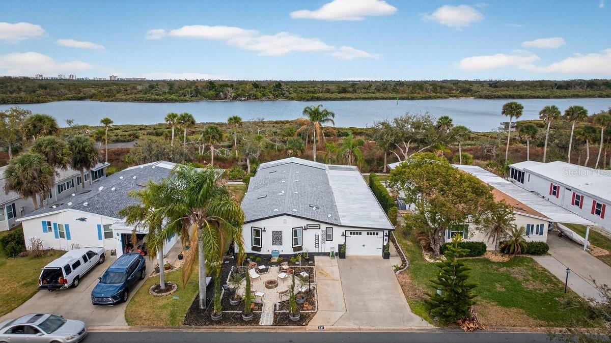 Perfectly positioned along 65 feet of direct Intracoastal Waterway frontage within the highly sought-after, guard-gated community of Edgewater Landing, this extraordinary 3BR/2BA/1-car garage residence redefines what manufactured home living can be. Known as the “condo alternative,” Edgewater Landing is an award-winning active 55+ community in Edgewater, Florida—voted one of the 50 Best Communities to Retire to—with a nearly $5M recreation center (currently under construction) recognized as #1 in America by the National Home Builders Association. This one-of-a-kind home has been completely transformed inside and out with elevated finishes rarely found at this price point, beginning with its striking board-and-batten Hardie-board exterior and fresh paint. Set along the riverfront walking path, the charming front garden and seating area invite friendly conversations with neighbors strolling by, while a screened lanai breezeway connects the garage, storage room, and main entry. Step inside and sweeping river views immediately command attention, showcased from nearly every room. The open living room features a fireplace and flows into a dining room with transom windows and beamed ceiling, leading to a showstopping chef’s kitchen with solid wood cabinetry, granite counters, full-height backsplash, stainless refrigerator and dishwasher, and an impressive $8,000 six-burner Italian gas range with custom hood that complements the cabinetry. A massive island with sink and abundant storage anchors the space, while two wide openings lead to an expansive, nearly 40-foot air-conditioned Florida room complete with wet bar, wood cabinets, granite counters, and wine cooler—perfect for entertaining as yachts glide past. Down the hall are two guest bedrooms, a well-appointed hall bath, and a spacious indoor laundry room with exterior access, while the gracious primary suite offers double closets and distinctive barn doors—collected from world travels—opening to a spa-like bath with clawfoot tub, separate shower, enclosed water closet, and dual vanities. Throughout the home, intricate tile flooring, designer lighting, and abundant natural light elevate the ambiance. Beyond the home, residents enjoy 24-hour security, clubhouse, heated pool, fitness center, dance floor, catering kitchen, outdoor BBQ and picnic areas, bocce ball, shuffleboard, tennis and pickleball courts, miles of scenic walking trails, two fishing docks, private boat ramp, canoe and kayak racks, plus RV and boat storage—an unparalleled waterfront lifestyle that truly embodies the Florida dream. ALL INFORMATION IS ASSUMED ACCURATE BUT NOT GUARANTEED. ALL MEASUREMENTS ARE APPROXIMATE. BUYERS AND THEIR AGENTS SHALL VERIFY ANY INFORMATION DEEMED IMPORTANT TO THEM.