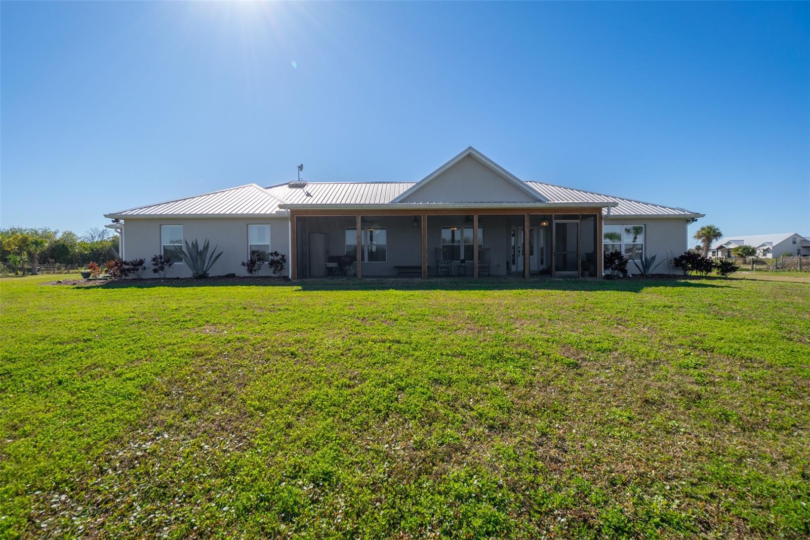 This 2020-built, 4-bed, 2-bath home sits on 3.18 tranquil acres! Enter through the automatic gate into your fully-fenced paradise featuring luxury vinyl plank flooring and an open floor plan. The chef's kitchen showcases an island with built-in microwave drawer, pantry, coffee bar, and dual reverse osmosis systems for purified water. The flex room includes built-in shelving and Murphy bed—perfect for guests or a home office. The primary offers his and hers walk-in closets, dual vanities, and an oversized shower. A metal roof and energy-efficient impact-resistant doors and windows ensure lasting comfort and peace of mind. Outside, enjoy painted porches overlooking your stocked fishing pond with dock. Separate irrigation for year-round gardening, and a utility shed with internal water system enable true homestead living. A 2-car epoxy-floored garage and a carport provides plenty of covered parking for your RV or boat. Perfectly positioned just 15 minutes from Space View Park for spectacular rocket launches, 30 minutes from Kennedy Space Center and Playalinda Beach, 20 minutes from Merritt Island Wildlife Refuge, and 50 minutes from Orlando Airport, enjoy peaceful country living with easy access to Florida's premier attractions. Don't miss out on your dream retreat!