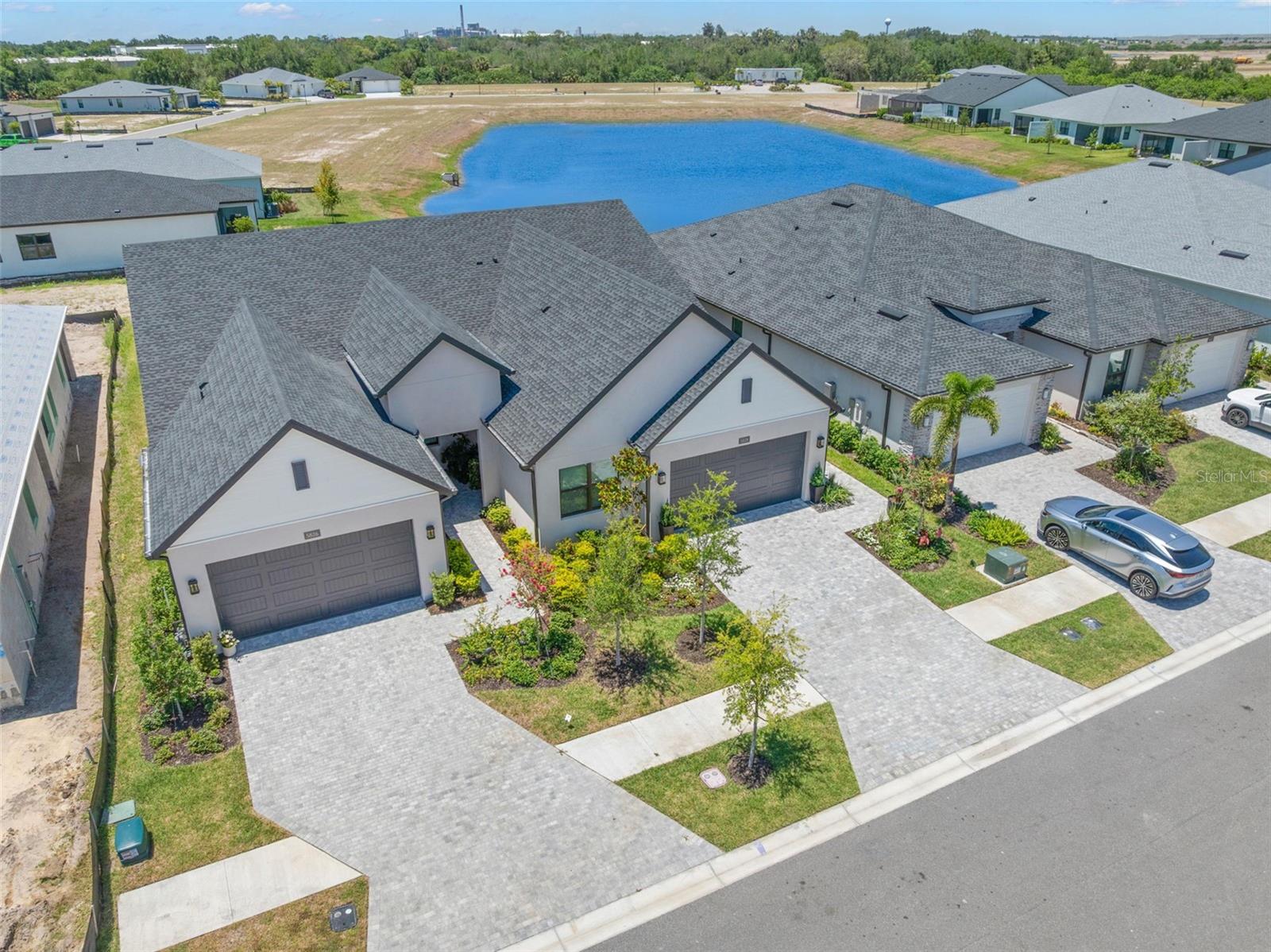 Experience the active lifestyle at Regency at Waterset, the only 55+ low-maintenance neighborhood within the established Waterset master-planned community in Apollo Beach. This exclusive gated enclave offers resort-style amenities reserved for Regency residents, creating the perfect setting for recreation, relaxation, and social connection. Built in late 2024 by Toll Brothers, this Tern floor plan with the sought-after Modern Ranch elevation offers 3 bedrooms, 2 bathrooms, a 2-car garage, and 1,805 sq. ft. of living space. Designed for both everyday living and entertaining, the open-concept seamlessly connects the spacious living room, dining area, and gourmet kitchen that showcases shaker-style cabinetry, Quartz countertops, a timeless backsplash, a built-in wall oven/microwave, and a GAS cooktop. A large center island with bar seating serves as the heart of the home, provides casual dining and a gathering space.  The outdoor living space has been thoughtfully enhanced beyond the original builder design to create a backyard retreat. From the screened lanai with retractable privacy shades to the expanded brick paver patio, every detail has been carefully designed for year-round Florida living. Custom enhancements include a decorative retaining wall with raised landscape beds, lush colorful and tropical landscaping, a soothing water feature, and serene water views that create a private setting for relaxing or entertaining. The thoughtfully designed split floor plan places the spacious primary suite at the rear of the home, offering added privacy and peaceful backyard and pond views. The primary suite features a luxurious en-suite bathroom with dual sinks, Quartz countertops, an oversized frameless glass walk-in shower with a built-in bench, a separate water closet, and a spacious walk-in closet with custom organization. Two generously sized secondary bedrooms provide comfortable accommodations for guests while offering the flexibility for dual use as a home office, hobby room, den and more! The full guest bathroom continues the home's stylish design with shaker style cabinetry, Quartz countertop, and has a tub/shower combination. The interior laundry room offers upper storage shelving, workspace, and a full-size washer and dryer.  Additional features include newly installed laminate flooring over the existing tile, a retractable screen door, vented microwave, tray ceilings, recessed lighting, updated ceiling fans, epoxy-coated garage floor, and remaining transferable builder structural/mechanical warranties, along with applicable manufacturer warranties and the golf cart is available for purchase. Residents enjoy exclusive access to The Cove, a 14,800-square-foot amenity center featuring a resort-style pool and spa, state-of-the-art fitness center with yoga studio, game room, pavilion with grill and bar, pickleball, tennis, and bocce courts, a dog park, walking trails, and a full calendar of clubs and activities curated by the on-site Lifestyle Director.  This comunity allows for 6 month rentals and is PET FRIENDLY with no weight limitations! The low quarterly fee includes high-speed internet, cable TV, lawn maintenance, exterior painting, and roof repair/maintenance and replacement providing a truly low-maintenance lifestyle in a non flood zone location and FHA, VA, Conventional Financing Welcome!