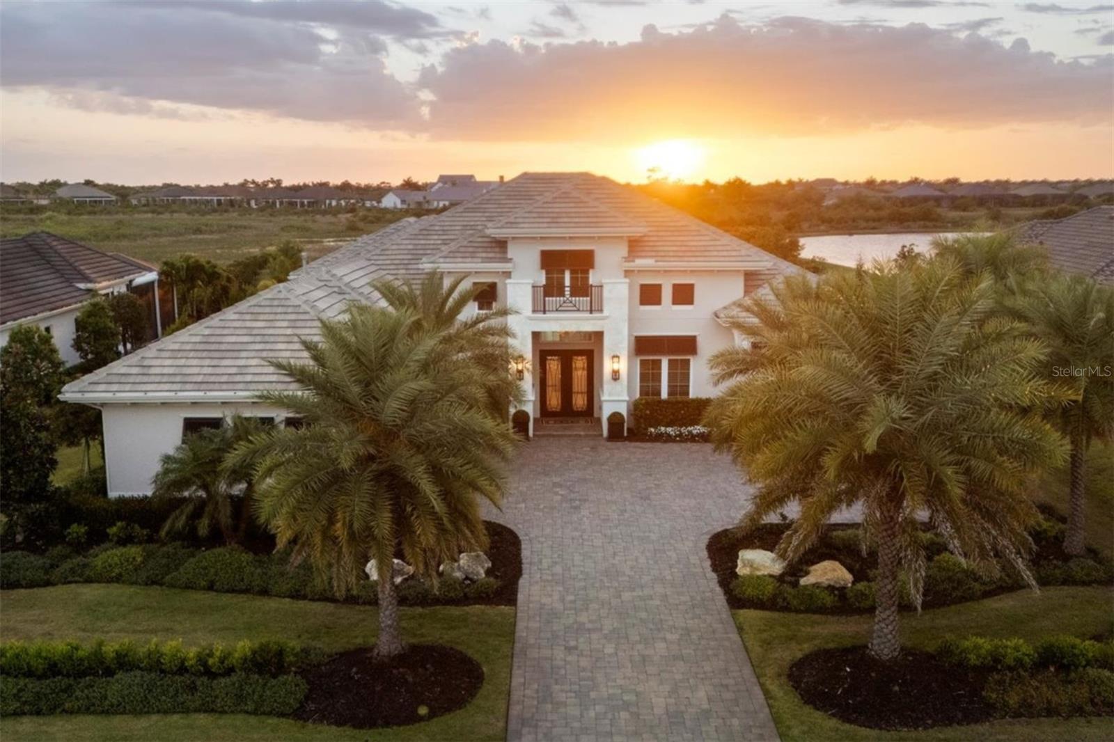 Under contract-accepting backup offers. Experience elevated Florida luxury in The Lake Club with this exceptional Stock Signature Gardenia III residence, offering 4,139 square feet of meticulously customized living space. Designed to seamlessly blend indoor and outdoor living, this open-concept home features 4 bedrooms plus a den and expansive bonus room, along with 5.5 baths—each bedroom boasting its own private ensuite. From the moment you enter through the double iron doors, you’re welcomed by a stately foyer and grand great room with soaring 15-foot coffered ceilings, refined by crown molding, porcelain tile flooring, designer lighting, and solid core doors throughout. At the heart of the home, the chef’s kitchen impresses with Britannica Cambria quartz countertops, a massive island with additional storage, upgraded JennAir stainless steel appliances, custom modern vent hood, under-cabinet lighting, and a walk-in pantry with wood shelving. The adjacent dining space is highlighted by a striking glass-encased illuminated wine wall, perfect for entertaining. A private casita—accessible from the lanai—offers a full ensuite bath and kitchenette with beverage cooler, ideal for guests. Step outside to an expansive marble-tiled lanai featuring a gas fireplace with newly installed custom tile surround, outdoor entertainment center, and a fully equipped summer kitchen with bar seating, grill, sink, and beverage cooler. Panoramic screens frame tranquil preserve and stunning sunset water views with complete privacy. The resort-style saltwater pool is a showstopper, complete with LED lighting, Pentair gas heater with smart capabilities, sun shelf, spa, swim-out bench, and elegant deck jets. The luxurious primary suite is a private retreat with seating areas, French doors to the lanai, dual walk-in closets with custom showcase organizers, and a spa-like bath with freestanding soaking tub, dual vanities, and walk-in shower. A versatile bonus/media room offers a waterfall-edge dry bar, beverage cooler, ensuite pool bath, and walk-in closet—perfect as a fifth bedroom or entertainment space. Additional highlights include a 3-car side-entry garage with epoxy floors, mini-split AC, high-lift door for car lift capability, and added blown-in attic insulation. Tech aficionados will appreciate the Sonos sound system throughout the home and Uxari security system. Hurricane impact windows, sliders, and doors provide peace of mind. The home is further equipped with an in-wall pest control system for added convenience, as well as a Culligan hybrid water softener and whole-home filtration system for enhanced water quality. Recent upgrades include professionally sealing the driveway and lanai, along with a preventative roof treatment designed to inhibit organic growth and maintain long-term curb appeal. Over $500,000 in premium upgrades, including $75,000 in lush, enhanced landscaping, this home is a showstopper! With no neighbors in sight and thoughtfully curated high-end finishes at every turn, this one-of-a-kind residence delivers the ultimate in privacy, sophistication, and Florida lifestyle living.