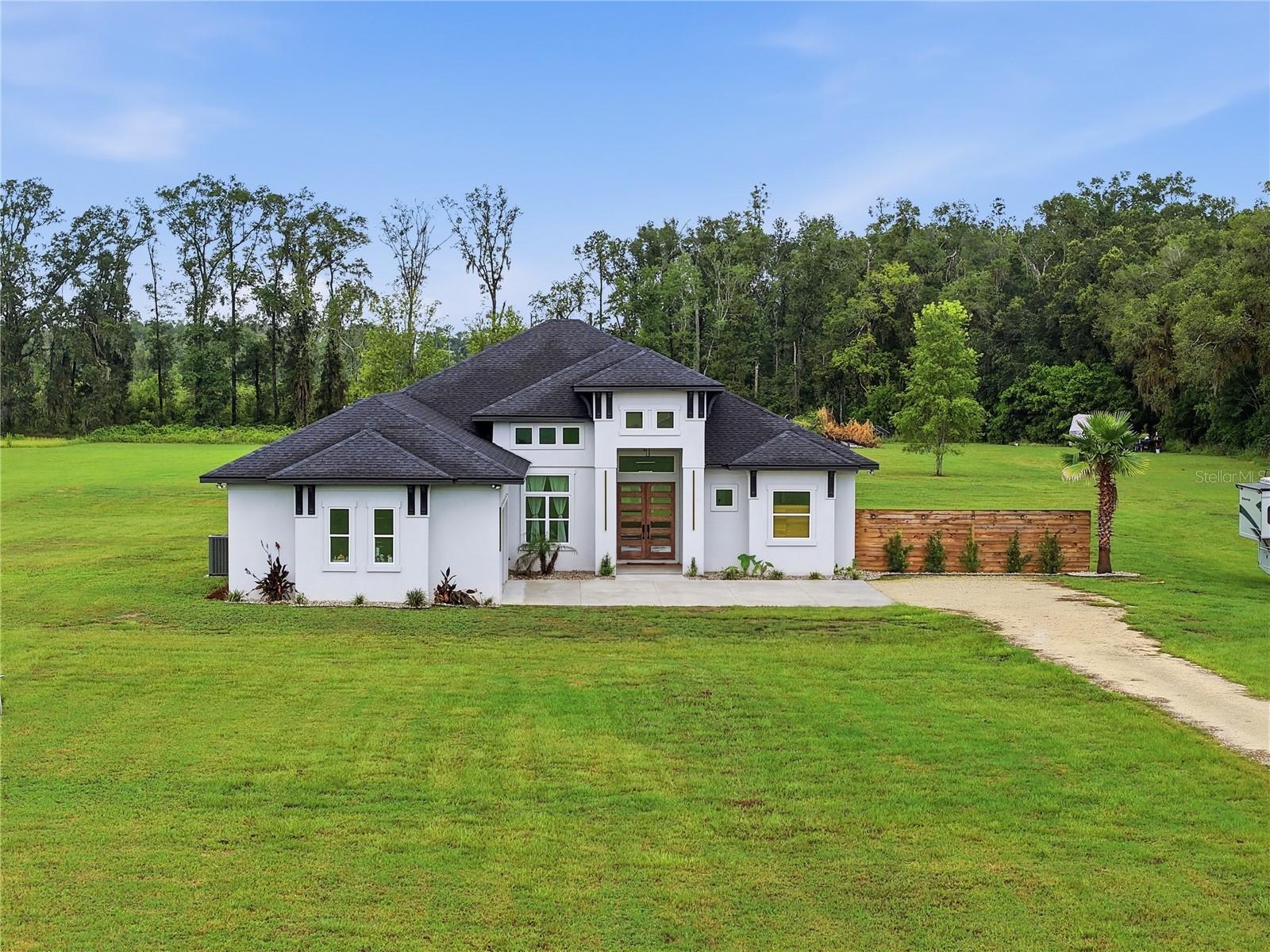 Set on just under 11 private acres in one of Alachua's most desirable locations, this custom-built home offers the rare combination of privacy, luxury, and convenience. Built with reinforced concrete block construction for lasting durability and added peace of mind, it's just minutes from I-75, shopping, and restaurants while offering peaceful country living without sacrificing everyday amenities.
Inside, the thoughtfully designed floor plan features 4 bedrooms, 4 full bathrooms, a dedicated office, soaring ceilings, and high end finishes throughout, including porcelain tile flooring, quartz countertops, and marble tile bathrooms. The chef's kitchen is built for both everyday living and entertaining with custom cabinetry, a suite of KitchenAid appliances, double wall ovens, a large center island with abundant storage, and an oversized walk-in pantry. Custom built-in closet systems provide exceptional organization throughout the home.
The nearly 800 square foot screened lanai extends your living space outdoors with a built-in grill, sink, and plenty of room to relax or entertain. When the day is done, the spacious primary suite provides a peaceful retreat, complete with a private infrared sauna.
Outside, the possibilities are endless. Whether you envision horses, a barn, a workshop, or a pool, the 10 usable acres provide the space and flexibility to make it your own. Fiber internet, an oversized laundry room, and a storage shed add even more value to this exceptional property.
Luxury finishes, usable acreage, and a location that offers both privacy and convenience make this a rare opportunity in today's market.