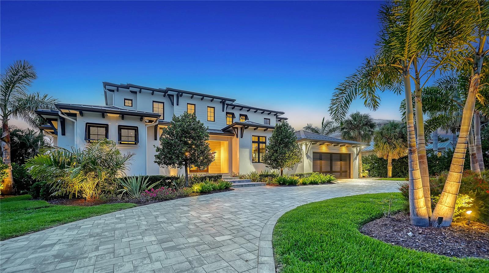 Built in 2022 by Voigt Brothers and designed by Arieno Custom Home Design, this new impeccable waterfront estate pairs sleek contemporary architecture with the comforts of elevated Bird Key living. Nestled along deep sailboat water just off Sarasota Bay, this Bird Key home spans over 4,700 square feet of beautifully finished interiors, seamlessly integrated with an expansive outdoor living experience. A pavered circular driveway framed by manicured landscaping welcomes you to this modern coastal residence. The elevated two-story design features a durable metal roof, impact-rated glass throughout, and an oversized two-car garage complete with epoxy flooring, mini-split A/C, storage, and elevator access. Inside, a blend of thoughtful engineering and elegant design unfolds—highlighted by solid hardwood floors, soaring 10’ and 12’ ceilings, Lutron-controlled lighting and shade systems, and walls of pocketing sliders that merge indoor and outdoor spaces with effortless grace. The heart of the home is a gourmet kitchen designed to both impress and perform. Anchored by a massive quartz-topped island, it features professional-grade Wolf appliances, hidden range hood, double built-in ovens, 6-burner gas Wolf cooktop with pot filler, and custom cabinetry offering abundant storage. A wine cooler with refrigerator drawers, prep sink, and dedicated Butler’s pantry with built-in desk enhance everyday functionality. This culinary hub flows into the dining room and great room, where a gas fireplace, tray ceiling, and custom floating shelves set a refined tone. The main-level primary suite offers a private retreat, with vaulted ceilings, its own dedicated laundry room, French door access to the terrace, a spa bath with soaking tub and rainfall walk-in shower, and a custom closet system designed to accommodate two wardrobes. Completing the main level is the office and impressive club room that offers additional lounge space with media potential, opening directly to the outdoor lounge for effortless entertaining. Upstairs, a loft-style family room currently serves as a fitness area, alongside three spacious guest suites with walk-in closets, a second laundry room, and a morning bar for added convenience. Take the elevator or ascend the bespoke staircase to access every corner of this thoughtfully designed home. Outside, two levels of resort-style entertaining spaces include a covered lanai with summer kitchen, electronic screens, and multiple seating areas. The heated pool and spa feature a sun shelf and tranquil waterfall. At the water’s edge, a new seawall supports a dock with four-post platform lift, offering direct access to the open waters of Sarasota Bay and beyond. Located in the sought-after Bird Key neighborhood, residents enjoy a private island lifestyle just minutes from downtown Sarasota, St. Armands Circle, and Lido Beach. Indulge in boutique shopping, fine dining, and the area’s renowned cultural scene including theaters, art galleries, and the marina. Optional membership to the Bird Key Yacht Club offers additional opportunities for boating, tennis, and social engagement. This is coastal living redefined—crafted with intention, and ready for your next chapter.