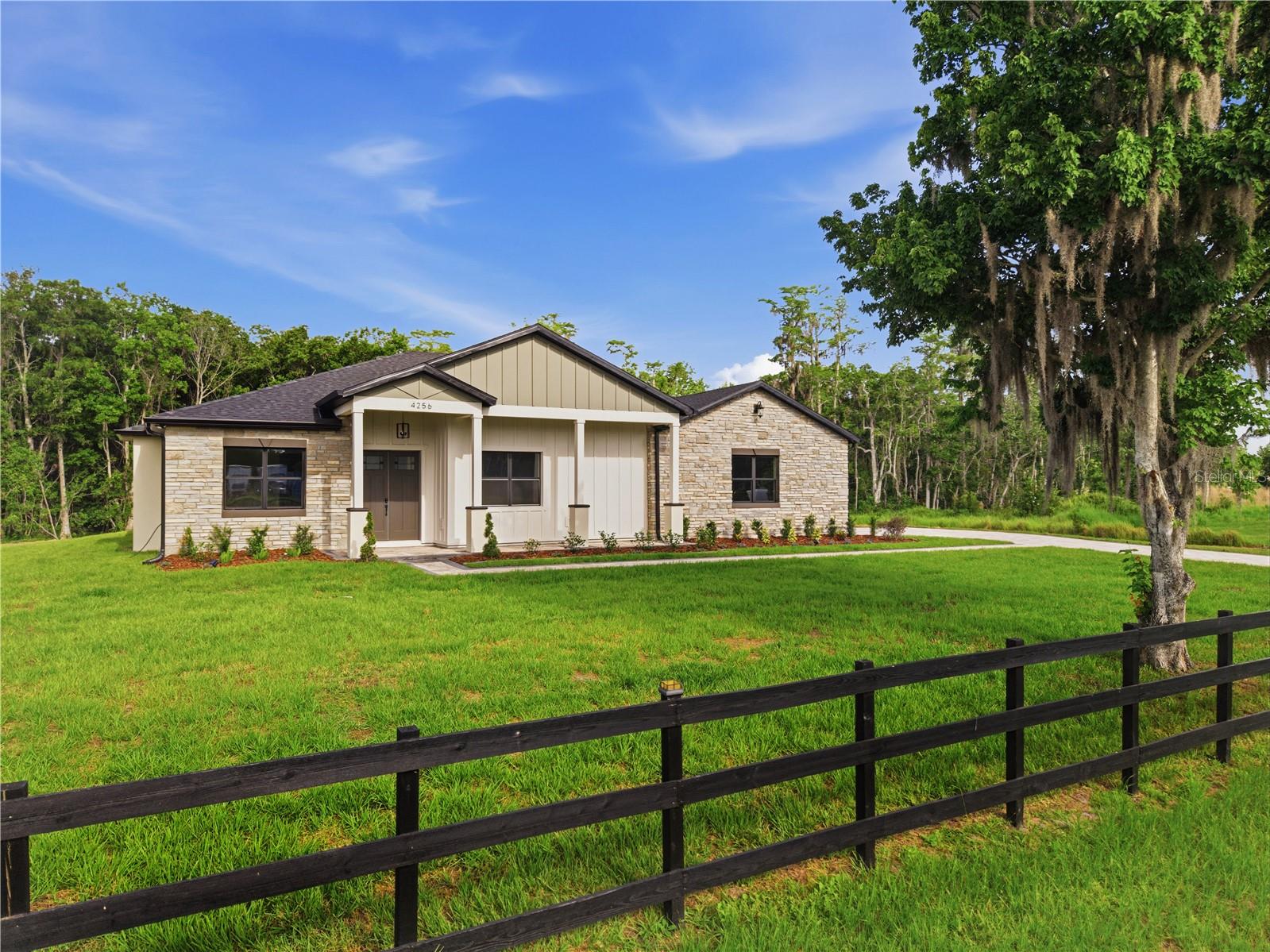 BRAND NEW CUSTOM BUILT HOME on 2.24 acres!!  4-bedroom, 2.5-bathroom home offers thoughtful design and quality finishes throughout, starting with grand double entry doors, 10-FOOT CEILINGS, VAULTED and TRAY ceilings that create an open, airy feel from the moment you walk in. Stunning open-concept living area featuring a custom floor-to-ceiling electric fireplace accent wall with designer vertical paneling, floating wood shelves, built-in cabinetry, and a decorative exposed beam. The spacious great room is enhanced by ENGINEERED HARDWOOD FLOORING, recessed lighting, and a modern oversized ceiling fan, creating the perfect blend of style and functionality. All accented by 6-inch baseboards, solid core shaker doors, STONE exterior accents, and a tongue-and-groove ceiling detail that adds warmth and character as you walk into your new home. The kitchen is equipped with slim shaker cabinetry with upper and lower cabinet lighting, QUARTZ countertops, STAINLESS steel appliances including a glass cooktop, convection oven and microwave combo, refrigerator dishwasher, garbage disposal, soap dispenser, and pot filler, plus a butler pantry with a Costco-style door for generous additional storage. A large chandelier anchors the dining room for large gatherings. The interior laundry room includes a sink, cabinetry, and washer and dryer hookups for added convenience. Bathrooms feature vanity mirrors with sconce lighting, exhaust fans, and automatic toilet openers. The spacious primary suite features dual sinks, a relaxing garden tub, walk in shower with a convenient shampoo NICHE. Custom deisgned walk- in closet complete with built in drawers and quartz countertops. The epoxy-floored 2-car garage adds a clean, finished touch along with a sink. Outside, the covered back porch showcases board-and-batten ceiling detail with recessed lighting and opens to a 20x30 extended paver patio and fully equipped summer kitchen — a functional setup for outdoor entertaining. The property also features a private pond, lush landscaping, columns, gutters and soffits, outdoor and floodlighting, a Ring camera at the front door, a shingle roof, and a well house. LOCATED IN CENTRAL FLORIDA CLOSE TO BEACHES AND DOWNTOWN ST. CLOUD for local shopping and dinning. Schedule your showing today. You will fall in love with this home so come by and check it out for yourself.