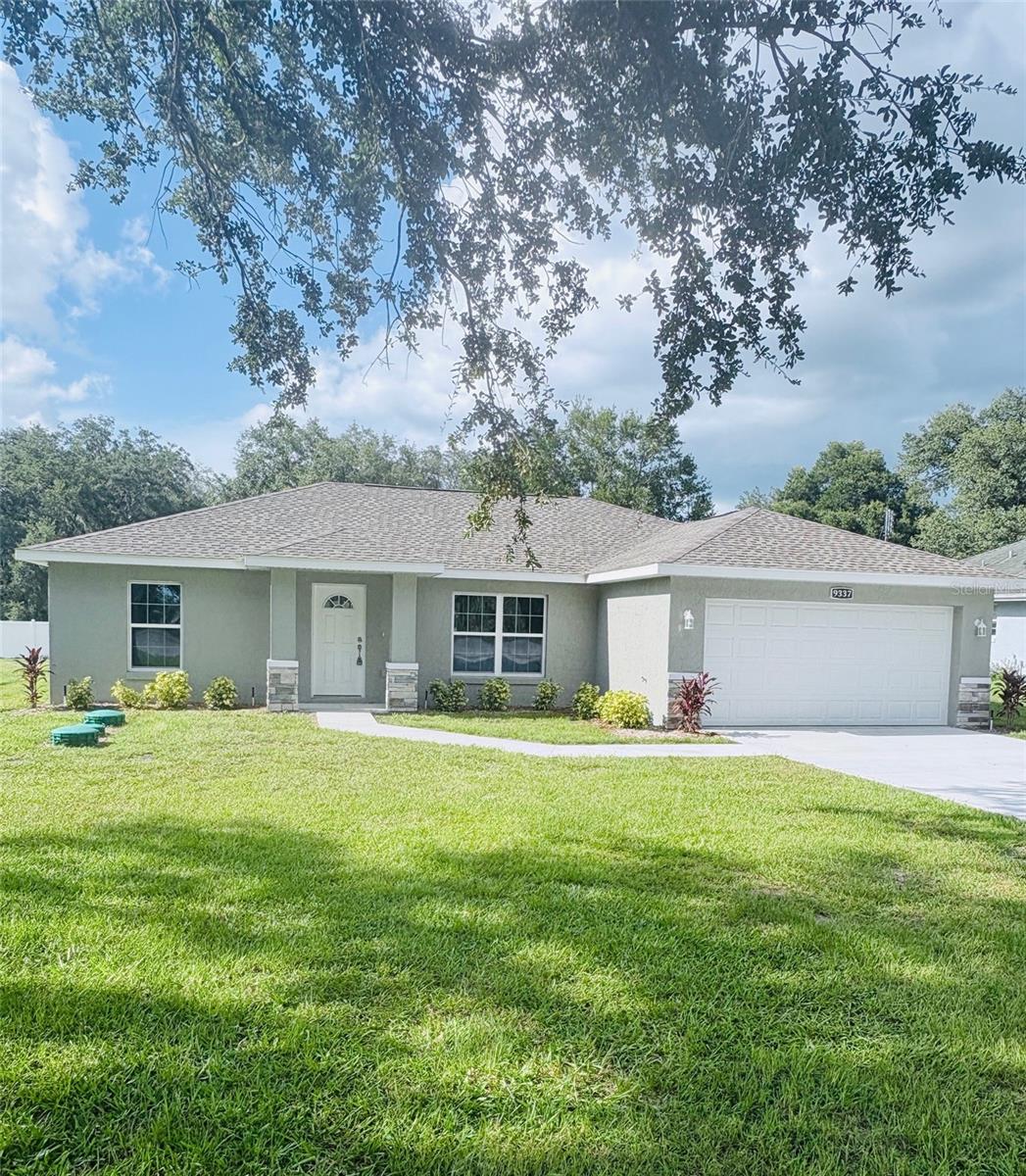 This 2025 St. Michael model home is a block construction property located within walking distance to the VA Veterans Clinic near The Villages. The home sits on a .31-acre lot and offers no HOA, no 55+ restrictions, no CDD, no flood zone, and no other restrictions. With over 2,090 total square feet, the spacious open-concept living area is perfect for entertaining. The kitchen is elegantly designed with granite countertops, 42-inch wood cabinets with soft-close system and crown molding, a large multifunctional island with storage, electrical outlets, and bar seating, a stainless steel double-bowl apron sink, and Whirlpool appliances including a microwave over the range. The interior also features a generous laundry room with cabinetry. The master suite includes a walk-in closet and a master bathroom with tiled walk-in shower, glass enclosure, granite countertops, dual faucets, and a wall-mounted cabinet with mirror. Two additional guest bedrooms have abundant natural light and share a luxury bathroom with steel tub, tiled shower, granite countertop, wood cabinet, and linen closet. The 2-car garage provides access to the private patio and features an opener, epoxy-treated floor, and side door. The patio offers space for outdoor activities and potential pool installation. Additional upgrades include marble window sills, upgraded lighting fixtures and ceiling fans, extra electrical outlets, a pre-wired alarm system, and an A/C unit located in the laundry room. The lot is fully landscaped with sod, decorative stone accents, modern exterior colors, and city water. This home comes with a builder warranty and is conveniently located just minutes from The Villages, with easy access to restaurants, championship golf courses, and town squares. ¡Hablamos español!