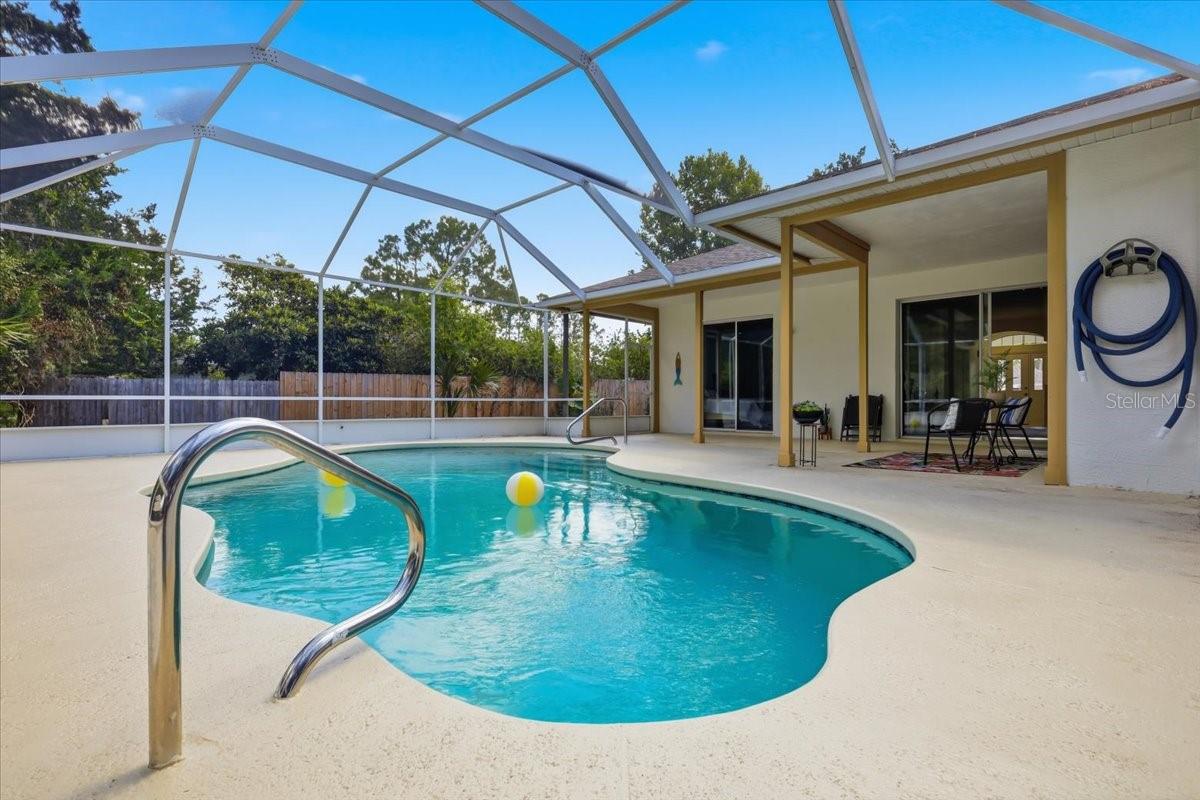 WELCOME TO YOUR PRIVATE POOLSIDE PARADISE! This incredible concrete block home offers the perfect combination of privacy, space, and value, tucked away on a quiet cul-de-sac in the highly desirable Pine Lakes Golf Community. Situated on an oversized 14,000+ square-foot homesite, the lush natural buffer creates a peaceful backyard retreat that’s hard to find!  From the moment you step inside, you’ll love the soaring ceilings, bright open floor plan, and fresh interior and exterior paint. This beautifully maintained 3-bedroom, 2-bath split floor plan was designed for comfortable living and effortless entertaining.   The heart of the home is the spacious eat-in kitchen featuring granite countertops, an abundance of white cabinetry, and an oversized breakfast bar that flows seamlessly into the main living area. A formal dining room provides the perfect setting for holidays and special occasions.  The owner’s suite is a true retreat with direct access to the pool, dual quartz vanities, and a spacious corner walk-in tiled shower. The secondary bedrooms feature beautiful wood flooring and impressive 9-foot ceilings, with one bedroom offering sliding glass doors leading directly to the pool area. The home also features tile flooring in the kitchen, bathrooms, and other wet areas.  Step outside and prepare to fall in love! The sparkling in-ground pool is surrounded by a completely re-screened enclosure and an oversized L-shaped covered lanai, creating the ultimate outdoor living space for weekend barbecues, family gatherings, or simply relaxing in your own private oasis.  Additional upgrades include a brand-new A/C (July 2026), Roof 2017, oversized two-car garage, and concrete block construction, with plenty of room for vehicles, storage, tools, and toys.  Best of all, you’ll enjoy NO HOA fees and NO CDD fees, giving you the freedom to truly enjoy your property. Whether you’re searching for your forever home, a seasonal Florida getaway, or a fantastic short-term rental opportunity, this home checks every box.  Located just minutes from golf, parks, shopping, restaurants, medical facilities, and only a short drive to Flagler’s beautiful beaches, this is Florida living at its best.   Homes offering this much privacy, this many updates, and a pool at this price don’t come along often. Schedule your private showing today before someone else does!