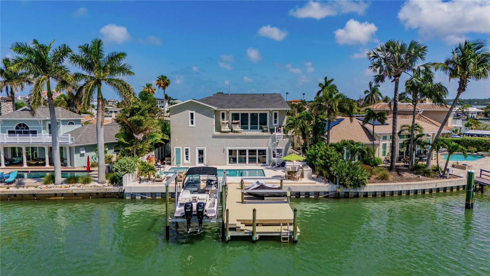 WATERFRONT LUXURY UNDER $2 MILLION IN NORTH REDINGTON BEACH. Offering nearly 3,800 square feet, 5 bedrooms, 5 full baths, a heated saltwater pool and spa, private dock, 12,000-pound boat lift, and sweeping Boca Ciega Bay views, this fully renovated waterfront estate delivers exceptional value in one of Tampa Bay's most desirable beach communities.  From the moment you enter, soaring ceilings and expansive water views create an unforgettable first impression. Designed for both everyday living and large-scale entertaining, the open floor plan seamlessly connects multiple living spaces with the chef's kitchen featuring granite countertops, stainless steel appliances, abundant cabinetry, a large center island, and breakfast bar seating.  The flexible layout includes three guest bedrooms and three full baths on the main level, including two ensuite bedrooms ideal for multigenerational living or hosting guests. Upstairs, a spacious waterfront family room opens to a frameless glass balcony overlooking Boca Ciega Bay. The oversized primary suite serves as a private retreat with stunning water views, a spa-inspired bath with soaking tub, walk-in shower, dual vanities, and generous closet space. An additional upstairs guest suite with full bath completes the second level.  Outside, enjoy your own private resort featuring a heated saltwater pool and spa, outdoor kitchen, tropical landscaping, new seawall, private dock, 12,000-pound boat lift, and additional lift for jet skis and water toys. Major updates completed between 2020 and 2024 include the roof, A/C systems, electrical panel, tankless water heater, pool, spa, dock, seawall, landscaping, and more.  For buyers seeking a move-in-ready waterfront home with space, luxury amenities, and direct boating access, 17081 Dolphin Drive represents one of the best values currently available on Tampa Bay's beaches.