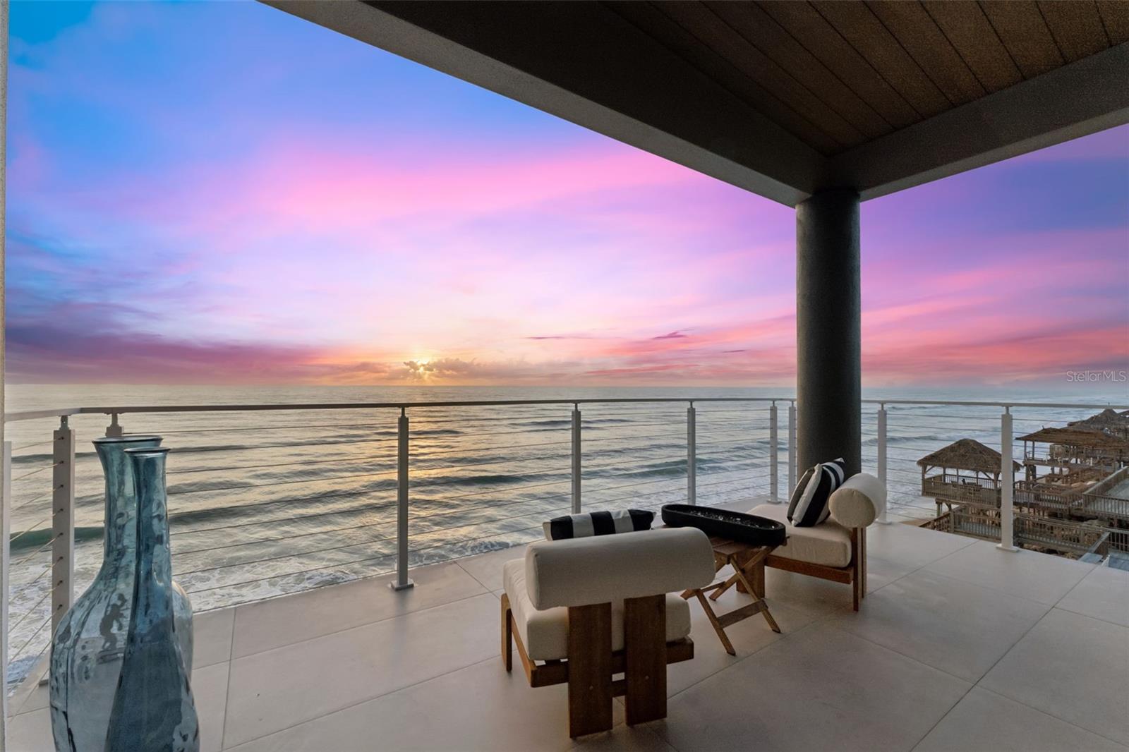Positioned on one of New Smyrna Beach's most coveted stretches of coastline, this extraordinary new construction residence sets an uncompromising new standard for oceanfront luxury. Engineered on 36-foot concrete pilings and built to withstand the full force of Florida's coastal climate, this is a home designed not just for beauty, but for generations.
One detail stops every visitor cold: floor-to-ceiling windows spanning the entire length of the home on every level. The Atlantic Ocean is not a view you look toward, it is a presence that fills every room, every corridor, every waking moment. A private elevator serves all three levels, ensuring seamless access throughout the home.
The heart of the home lives at the top. The third-floor great room is a seamless union of chef's kitchen, dining, and living space where panoramic Atlantic views pour through soaring windows from every angle. The kitchen is anchored by a massive quartz island and a professional-grade ILVE Italian 8-burner range; hand-assembled in Campodarsego, Italy to the exacting standards of Michelin-starred kitchens worldwide. Custom cabinetry conceals an integrated refrigerator, freezer, and dedicated wine refrigerator. Step through to the expansive third-floor balcony, and the full sweep of the beach unfolds before you. Back inside, a book-matched Dekton stone wall anchors the living room, dramatically framing both a large-format television and fireplace within its sweeping form. Bespoke accent lighting throughout transforms every interior into something cinematic after dark.
The second level houses the bedroom suites, including a primary suite opening directly onto its own private balcony overlooking the beach; wake to the surf, step outside to the salt air, and watch the morning light move across the water without leaving your room.
The first floor offers a thoughtfully designed two-bedroom guest wing with its own full kitchen and living area; ideal for extended family, visiting guests, or a live-in caretaker, with complete separation from the main residence and its own ground-level patio opening directly to the beach.
Just minutes away, Canaveral National Seashore preserves over 57,000 acres of pristine Florida wilderness and one of the longest undeveloped stretches of Atlantic coastline on the East Coast. When town calls, legendary Flagler Avenue delivers independent boutiques, acclaimed farm-to-table dining, art galleries, and the kind of authentic local character that larger resort towns lost long ago.
This is not simply a home, it is a complete way of living, where the Atlantic fills every window on every floor and spills onto three levels of outdoor living. Opportunities at this level of quality, craftsmanship, and location are exceedingly rare.