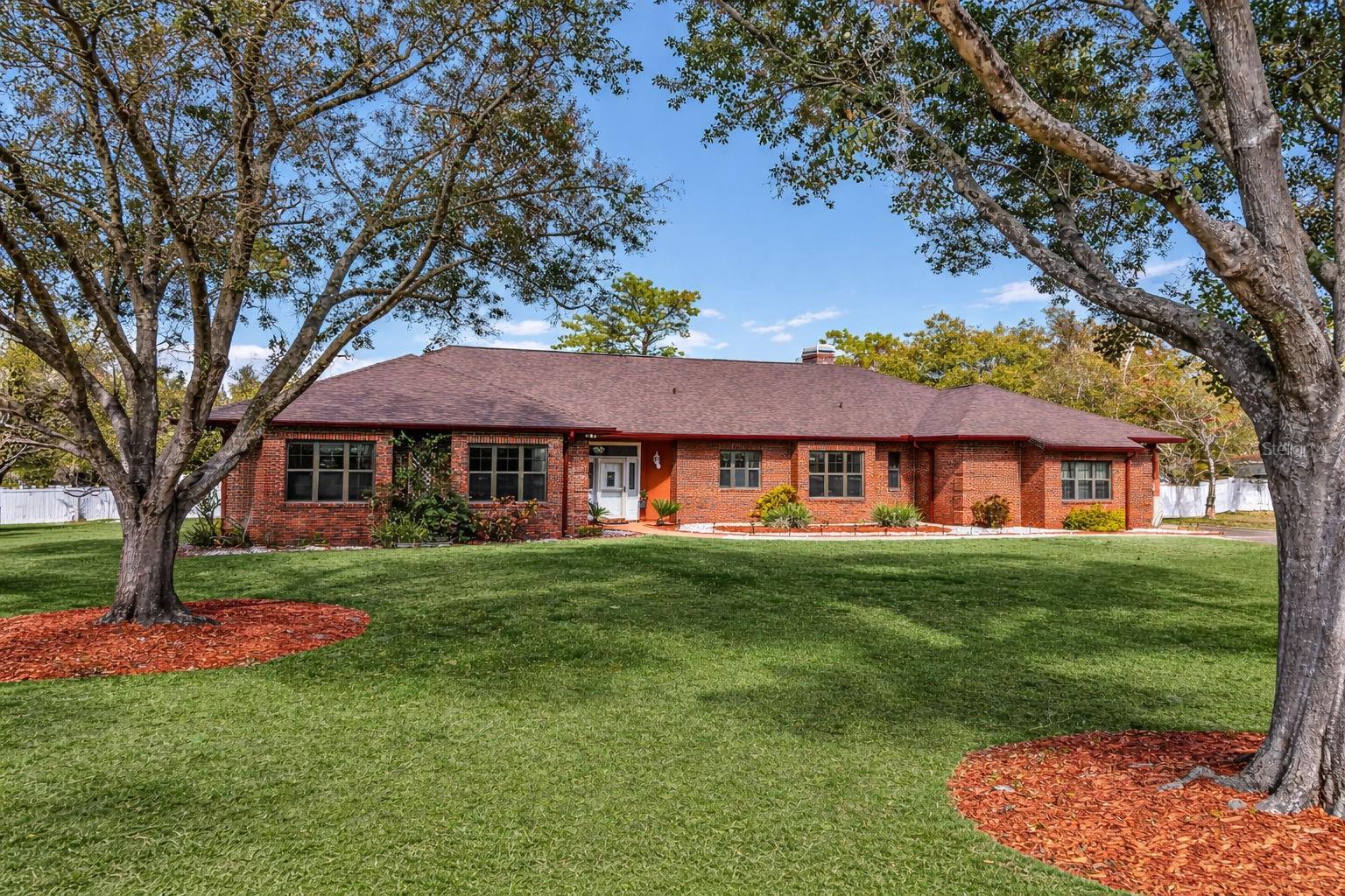 Welcome to this exceptional, one-of-a-kind brick estate home offering over 3,000 square feet of living space, situated on over one acre in the highly desirable Mill Creek community. With timeless curb appeal, a sprawling layout, and incredible indoor-outdoor living, this property offers the perfect blend of privacy, space, and classic Florida charm. From the moment you arrive, you’ll be greeted by an expansive manicured lawn, mature shade trees, and stately brick exterior. Inside, the home opens to bright, open living areas featuring soaring ceilings and elegant marble flooring throughout the foyer, dining room, kitchen, and laundry room. This thoughtfully designed split floor plan includes 4 generously sized bedrooms, 3.5 bathrooms, plus a dedicated office/den, providing flexible space for families, guests, or working from home. The oversized primary suite serves as a true retreat with ample room, abundant closet space, and a spacious en-suite bath. Secondary bedrooms are well-proportioned and conveniently located near full bathrooms. The updated kitchen is designed for both functionality and entertaining, featuring wood cabinetry, Corian countertops, a large center island, built-in oven, stainless steel appliances, pantry storage, and an adjacent breakfast area. The kitchen flows seamlessly into the dining and family rooms, ideal for gatherings. The family room is anchored by a wood-burning fireplace, adding warmth and character. A bonus room with a full bathroom, privately located on the opposite side of the home, offers endless possibilities, perfect as a guest suite, game room, multigenerational living space, or private retreat. Step outside to your private backyard oasis, complete with a large screened-in pool (approximately 33’ x 14’) and expansive covered lanai, ideal for year-round enjoyment. The huge backyard with mature landscaping and fruit trees provides exceptional privacy with no rear neighbors, making it perfect for entertaining, relaxing, or enjoying the Florida lifestyle. Additional features include a spacious laundry room, ample storage throughout, and a large garage. Conveniently located near shopping, major highways, and top-rated schools, this home offers peaceful estate living with everyday convenience. Rare opportunity to own an over-3,000 sq ft home on acreage in Mill Creek. Schedule your private showing today.