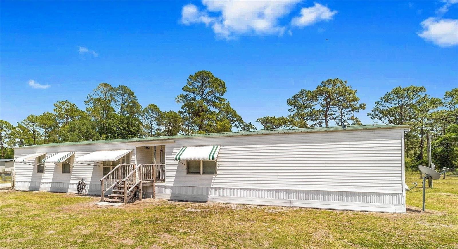 (Some pictures are virtually staged) RARE FIND_ 3/2 CLEAN Country Charmer has Everything you are looking for. Peace & Quiet, Room inside & out. Bring your toys, you have just under 3/4 acre to play. NO HOA, NO Rules. No Flood Zone. ALL the FREEDOM to live as you choose. One storage shed  comes with the home, (a second shed is available) all on the oversized lot you want. The Updated Features include: Fresh paint inside & out, pressure washed exterior, Modern Luxury Vinyl Plank FLooring throughout, NO CARPET.  METAL ROOF, Newer HVAC, 4" well for great pressure, Cozy FIREPIT is waiting. Its Summer-Its time for  campfires and SMORES! Your Kitchen has glass top stove, Lots of counter space, Built in additional storage for kitchen needs or for Books/Homework. Space to eat together ,everyone around the same table, over looking country views of open fields, trees, horses and cows. Exhausted after work? Come home to a Spacious Bathroom with His & Hers sinks, long counter, seperate shower and a LARGE SOAKING GARDEN TUB, you can actually lay down in. Primary Bedroom has HIS and HERS closets.  Guest Wing has TWO BEDROOMS & bathroom has a shower/tub combo . You found your  Forever Home. The bonuses don't stop on the inside. Outside you find  you are on a CORNER LOT , fully FENCED yard with a single & a DOUBLE GATE, large parking pad, AND...,the home has a SURVEY (saves you 400+ $$$) and an Engineering Cert for the tiedowns and permanent foundation($$$ 4K+) ,newer skirting complete with durable weed barrier thats weed eater proof. There are ALSO hurricane awnings on the windows, easy to secure for quick weather proofing. SAVES YOU EVEN MORE $$$ on INSURANCE. Serenity  and peace of mind, right here in Fort MCCoy. You can lead the quiet life but still be a short drive to needed shopping, yet be within an hour to 5 AMAZING Springs, right here in the Ocala National Forest. Forget the Beach with sharks. Go to Juniper Springs and dive for sharks teeth, Go see the otters and monkeys at Silver Springs, Alexander Springs always has amazing sights, Salt Springs is literally around the corner....Glen Springs too..the list keeps going. Only an hour from world Famous Rainbow River or hour and a half from Daytona Beaach. or an hour and a half to the Gulf-Cedar Key. This is Central Florida living at its Best! Private but still just minutes to the local Grocery store, Local hardware & Feed store, Post Office, Library, Local Doctor, Hair Salon, Dollar General and strip mall. *Corner Lot * Freshly painted * Modern Washer & Dryer included