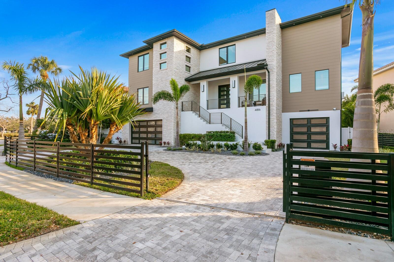 Experience refined modern living in this 2023-built home by Steven Anthony Luxury Homes. Built to the latest building codes with impact windows/doors, and elevated FEMA-compliant living for flood risk reduction. Enjoy refined finishes and superior appointments throughout with 4,728 SF Living Space / 7,873 Total Square Ft, including an oversized 3 car garage with possibility of parking up to 5 cars. A gated circular driveway leads to a striking three-story residence with 3-stop elevator service to all levels. The expansive great room boasts 10-ft ceilings, a custom feature wall, and sliding doors opening to the terrace. The gourmet kitchen features Wolf and Sub-Zero appliances, a sleek two-toned cabinetry, a quartz waterfall island, double ovens, a gas range with pot filler, and a walk-in pantry. The main floor includes an ensuite bedroom, a private office with a hidden closet, and a mudroom with a built-in bench and storage for added functionality. The second-floor primary suite offers a spa-inspired bath, a custom walk-in closet with built-in shelving, and a morning coffee bar with a sink and beverage fridge. Three additional ensuite guest bedrooms and a bonus room with a media closet and dry bar—all featuring custom shelving in the closets for optimized organization. Additional features include wide-plank hardwood flooring, statement lighting, security cameras, generator pre-wire, blinds package, and exterior screens. Outside, the heated saltwater pool, spa, fountain, and covered lanai create a private oasis for year-round enjoyment. Enhanced with an electronic gate, this estate ensures privacy, security, and uninterrupted comfort, all in a prime location near A-rated schools, fine dining, shopping, cultural attractions, Hyde Park Village, Tampa International Airport, and Bayshore Boulevard. This is luxury living at its finest in the heart of South Tampa.