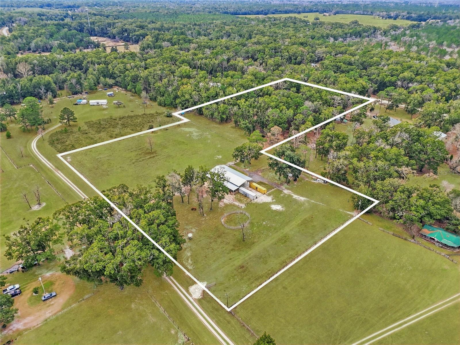 Rare opportunity to own 10 beautiful acres in Fort White, comprised of two connected, buildable 5-acre parcels—offering flexibility, privacy, and endless possibilities. The property provides the best of both worlds: one parcel fronts Freedom Court and is heavily wooded, creating a natural buffer and secluded homesite, while the second parcel fronts Cowpoke Court and is mostly cleared with scattered mature trees—ideal for a homesite, pasture, or additional improvements. Equestrian-ready, the cleared property is fully fenced and cross-fenced, making it perfect for horses or livestock. A spacious 84’ x 40’ pole barn with an additional 14’ x 84’ side features four horse stalls and a concreted wash rack. One side of the pole barn was started as a barndominium and includes a bathroom, offering potential to be finished out as living quarters, guest space, or a private office. Infrastructure is already in place, including a 3-bedroom house-sized septic system and a 4” well drilled to 100 feet. Shipping containers on the property will convey, providing ample additional storage. (RV and round pen do not stay.) Ideally located in North Florida’s springs region, this property offers quick access to the Santa Fe and Ichetucknee Rivers, making it perfect for kayaking, tubing, and outdoor recreation. You’re just a short drive to Gainesville for shopping, dining, medical facilities, and the University of Florida, while Lake City is also conveniently nearby for additional amenities. Whether you’re looking to build your dream home, create a working farm, or enjoy a peaceful rural retreat, this versatile 10-acre property is ready for your vision.