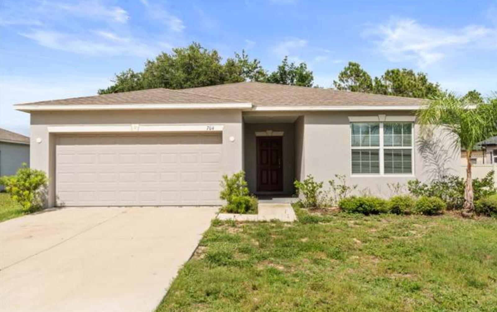 Welcome to a beautifully maintained 4-bedroom, 2-bathroom single-story home built in 2022 and offering modern finishes, an open-concept layout, and a spacious backyard backing to mature trees for added privacy. Step inside to a bright, open great room that flows seamlessly into a stunning kitchen featuring crisp pale shaker cabinets, quartz countertops, a full stainless steel appliance package, and an oversized center island with bar seating, perfect for entertaining or everyday family living. A walk-in pantry and indoor laundry room sit just off the kitchen for added convenience. The split floor plan places two secondary bedrooms and a full guest bathroom near the front of the home, one with a walk-in closet and one with a standard closet, sharing a clean, well-appointed bath with a tub/shower combo. A fourth bedroom offers flexibility for a home office, nursery, or guest room. Tucked privately at the rear of the home, the spacious primary suite features a large en-suite bathroom with dual vanities, a tiled walk-in shower with built-in bench seating, and a generous walk-in closet. Sliding glass doors off the great room open to a backyard with a concrete patio pad and plenty of green space to make your own, ideal for a future pool, garden, or outdoor entertaining area. Mature trees line the back lot, creating a quiet, private setting. Located in a peaceful Kissimmee neighborhood with easy access to major roadways, shopping, dining, and Central Florida's world-famous attractions. With its newer construction, modern finishes, and flexible layout, this home is truly move-in ready.