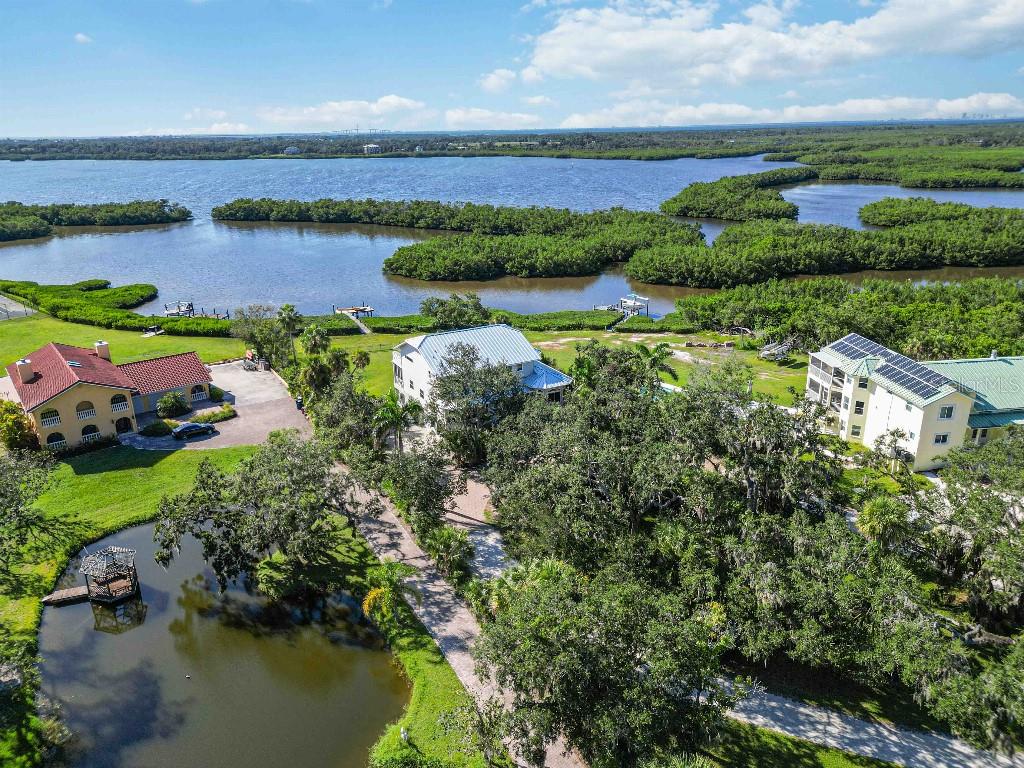 Enjoy panoramic sunset views of Terra Ceia Aquatic Nature Preserve from your back porch swing in this Key West contemporary custom built waterfront retreat set on 1.34 acres with over 50 mature varieties of native and exotic trees, shrubs, and plants. Hidden among the beautifully landscaped yard is an RV pad with electric and water hookups. The house offers 3306 sf with 3 bedrooms, 2 bathrooms, an open floor plan with spectacular views, and an elevator shaft. The updated kitchen features stainless steel appliances, granite countertops, and walk-in pantry. Recent updates include two full bath remodels, two walk in custom closets, wide plank oak floors, ivory Egyptian limestone floors throughout, hurricane impact windows, new metal roof, interior and exterior paint, siding, two Trane AC units, Rheem hot water heater, and alarm and camera surveillance system. Garage level offers over 1000 sf for 2+ cars, with plenty of space for storage and dream workshop, with an additional 1100 sf for workout space, game room, man cave/she shed and more. Steps away from your back porch go fishing, paddleboarding, kayaking or launch a boat from your own private pier. Outdoor amenities include two expansive fully screened in lanais overlooking the bay, outdoor shower, and spa connections.  Conveniently located with 10-minute access to Bradenton, 20 minutes St. Pete, 20 minutes to Sarasota, and 40 minutes to the Tampa International Airport.
With all of your modern day conveniences close by, when you arrive on this property one feels the worries of the day wash away, hidden in nature with acres of water views in your backyard, every day feels like a holiday.