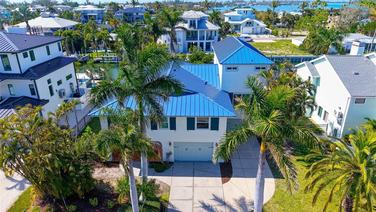 One or more photo(s) has been virtually staged. Boaters will love this spacious elevated home in a premier waterfront location on Longboat Key with dock, lift and by boat it is just four homes from the intercoastal, open bay waters and a short boat ride to the Gulf. Built for large gatherings, this home is beautifully designed with loads of gathering and entertaining spaces. The open plan home was thoughtfully designed with five bedrooms, four with en-suite baths. The kitchen features custom wood cabinets and granite countertops. Entertaining will be a breeze with two large gathering spaces, including a great room with dining area and adjacent bonus room that would be a wonderful media or game room. Ground level highlights include two bonus areas and a huge four-car garage. The composite dock has a 10,000-pound boat lift, water and electric. Recent updates include hurricane windows and doors (2025), metal roof (2025), pool equipment and pool heater (2025) and interior freshly painted. This location on Longboat Key can't be beat with community beach access just across the street, and a heated pool and boating in your own backyard. This is the ideal home to create wonderful island memories.