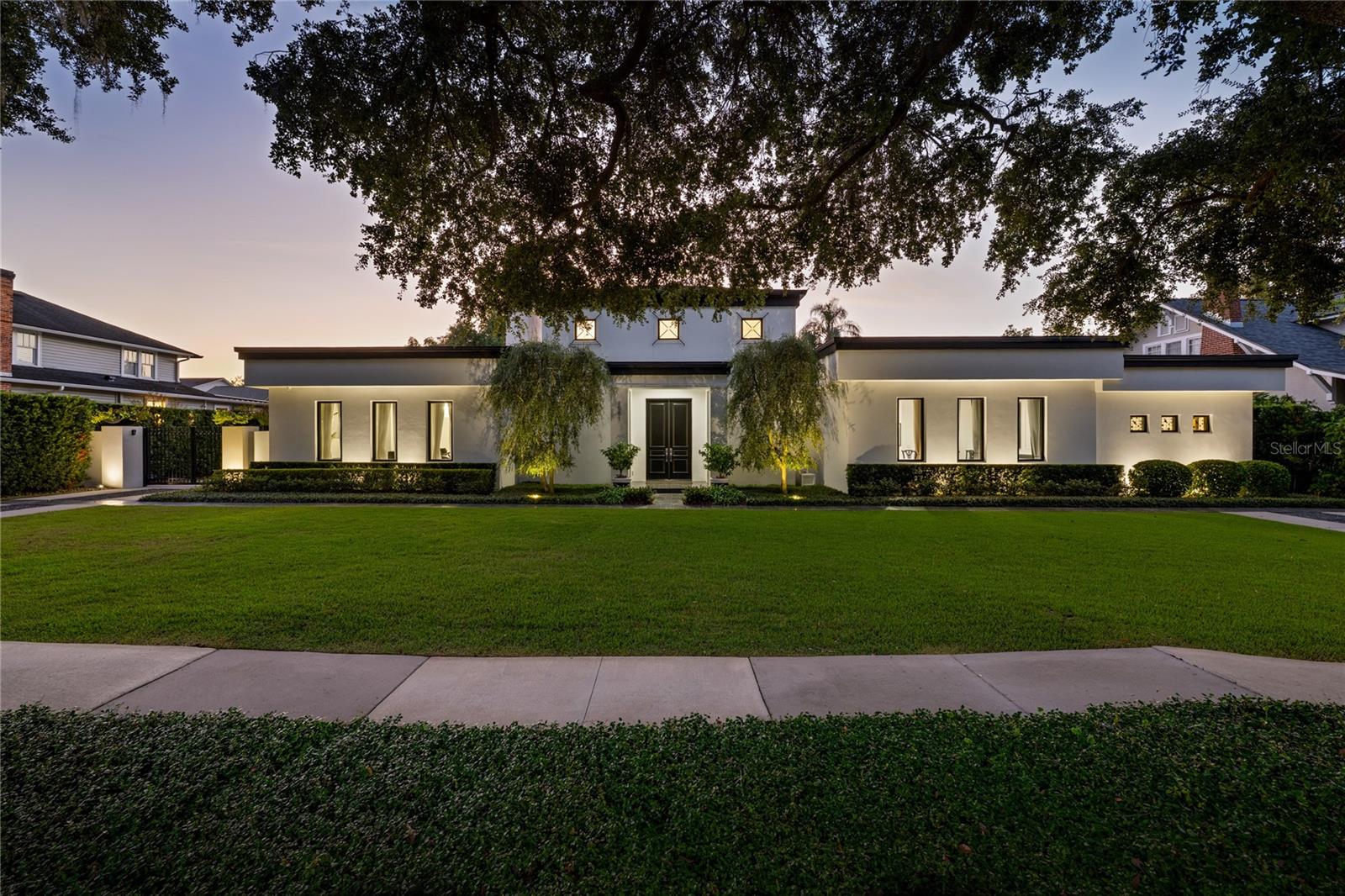 This exceptional Winter Park residence offers a floor plan rarely found in the area, with nearly all living spaces thoughtfully positioned on a single level for effortless everyday living. Completely rebuilt in 2018 by renowned custom builder Posada Homes, a member of the elite Master Custom Builders Council, the home blends modern design, crisp architectural lines, and timeless elegance across an expansive 0.39-acre lot along one of Winter Park’s most picturesque tree-lined streets. The home immediately captivates with its refined architecture and beautifully manicured grounds. Inside, sunlight streams through expansive windows, illuminating hardwood flooring, intricate millwork, and thoughtfully curated finishes that reflect the craftsmanship of a true custom build. Just off the foyer, a hidden wine room provides a sophisticated surprise, perfect for those who love to entertain. At the center of the home is the chef’s kitchen designed for both beauty and functionality. Outfitted with premium Thermador appliances, sleek quartz countertops, a generous center island, and custom cabinetry, the kitchen flows effortlessly into the expansive great room where high ceilings, designer lighting, and elegant architectural details create an atmosphere that is both inviting and refined. Tucked away for privacy, the primary suite is positioned just off a luxurious family room featuring custom built-ins and a gas fireplace. The primary suite itself is a true sanctuary, complete with a sitting area, private coffee bar, and a spa-inspired bath featuring dual vanities, a soaking tub, and an oversized walk-in shower. Rarely found in Winter Park, all bedrooms are conveniently located on one level, including two primary suites, allowing the home to deliver seamless livability without sacrificing architectural interest or sophistication. Upstairs, a private office, half bath, and bonus room provide the perfect space for work, media, recreation, or relaxation. Outdoors, the home transforms into a private resort-style retreat. A covered lanai overlooks the sparkling pool and expansive grounds, creating the ideal setting for entertaining or quiet evenings at home. Adding even more flexibility, a 252-square-foot detached studio currently functions as a gym but could easily become a summer kitchen cabana, guest retreat, or art studio. Located within walking distance of Park Avenue’s boutiques, restaurants, and cafés, and just moments from Rollins College and the Winter Park Chain of Lakes, this residence embodies luxury living at its finest. Don’t miss this rare opportunity to own one of Winter Park’s most outstanding homes. The current flooring offers a rich look, and for those who prefer a lighter palette, the seller is open to providing a credit toward flooring updates and coordinating the installation of new flooring if desired.