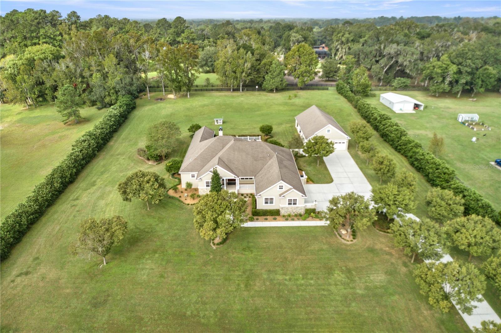 Discover an unparalleled level of luxury in this custom-built 4-bedroom, 3 full bath, and 2 half bath home, situated on nearly 4 acres within the prestigious Spring Grove Equestrian Community. This gated residence is a masterpiece of quality, innovation, and opulance. Constructed with superior Insulated Concrete Form (ICF) technology, it offers remarkable energy efficiency, longevity, and unmatched protection against severe weather events. The heart of the home is its gourmet kitchen, a chef's dream. It showcases solid surface countertops, beautifully crafted custom wood cabinetry, and an array of top-tier stainless steel appliances, including a Thermador refrigerator, range, and double oven. Equipped with a convenient pot-filler, cooking here is a seamless experience. An oversized island with a sink provides ample prep space for culinary creations. The expansive living area boasts 10-foot ceilings, crown molding, custom built-ins, and a cozy fireplace, creating an inviting atmosphere for relaxation and entertainment. The generously sized bedrooms come complete with built-in closets for added convenience, providing ample storage and organization options. This home also features a thoughtfully designed split bedroom plan, offering both privacy and functionality. Upstairs, a versatile bonus room provides an ideal space for an office, playroom, or game room. The property includes a 5-car garage setup, with two in the standalone garage/workshop, offering ample outdoor space. Beyond the main residence, you'll find the 30x38 workshop that's a haven for creativity, offering its own electrical panel as well as water connection, its multi-level with nearly 1,200 square feet of loft space that is ready to be transformed into a studio, a guest suite, or an entertainment area. Additionally, there is 40x38 under roof open space at the back of the workshop that can be converted to a barn or utilized for stall spaces. The outdoor oasis features a private pool area, perfect for cooling off on warm Florida days and hosting gatherings with loved ones. Additional unique features include an outdoor drainage system that effectively channels water from house gutters and surrounding grounds away from the home, a whole-house propane generator for added peace of mind and a unique barn owl house. Fruit trees grace the property, and a bridle run adjoins the property and extends behind the home into nearby neighborhoods, perfect for the equestrian enthusiast. This home is a true testament to the fusion of quality, efficiency, and luxury living—a rare opportunity you won't want to miss. Schedule your private tour today and experience this exceptional estate. New well in October 2023.