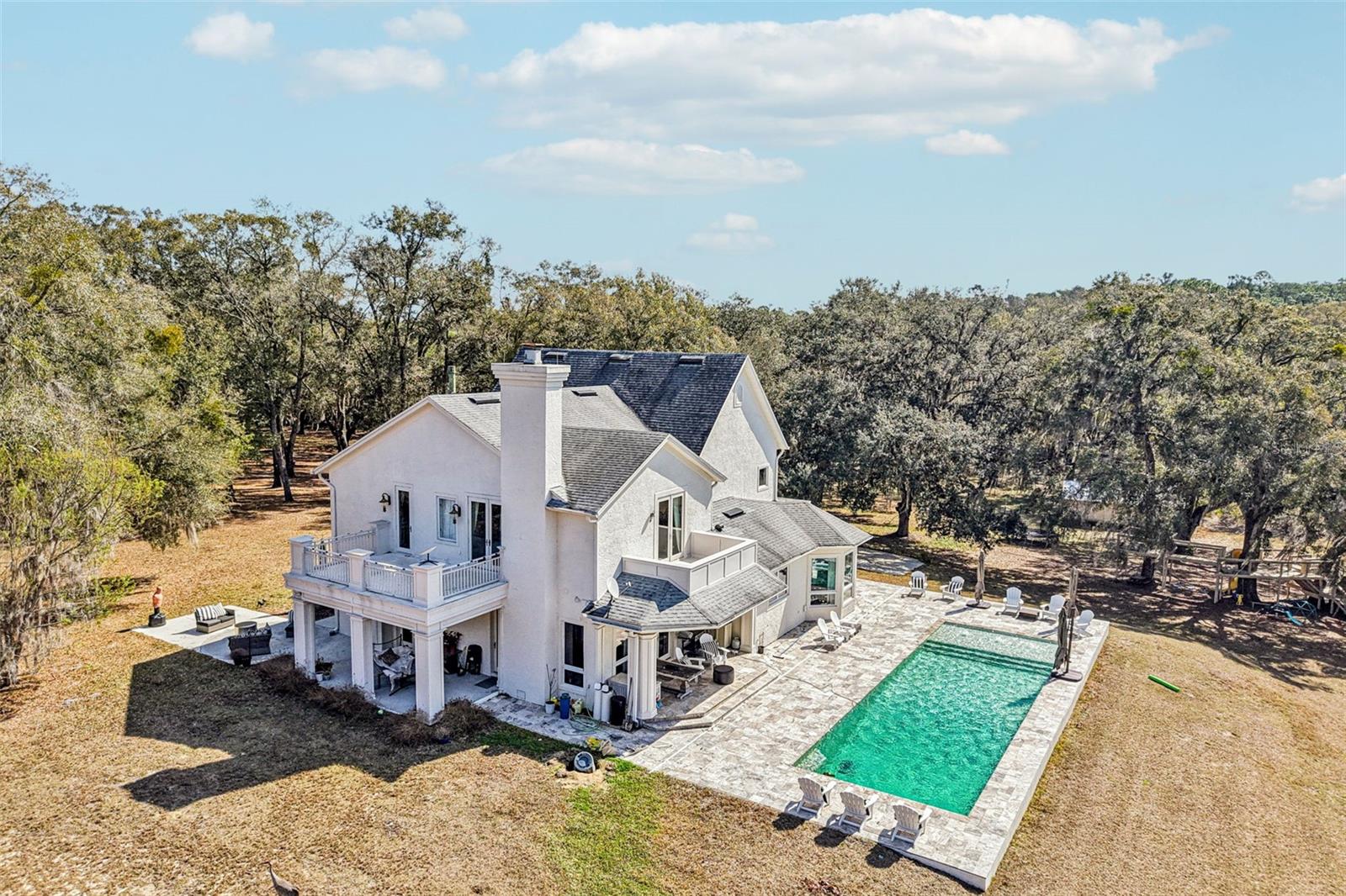 Looking for a Private Sanctuary nestled on just over 10 gentle rolling acres…  Look no Further! This Private Luxury Pool Home includes 4 Bedrooms (with separate office space easily used for 5th Bedroom) plus 3.5 Baths. The two-story traditional custom designed home offers unique features plus an expansive Saltwater Pool with Spacious Travertine Deck, BBQ area plus Portico Open to Front Patio and Rear Deck.  This unincorporated property is conveniently located near the impressive Black Bear Golf Community however, NO HOA.  As you enter, you will find your eyes are drawn to the exquisite Chandlier which adorns the foyer as well as the Circular Stairs, enhanced with Solid Wood Balusters leading to the 2nd floor. The 2nd Guestroom, just off the foyer, is currently used as the family TV Room. The extra wide 2nd floor Landing not only leads to the Master Suite and Upstairs Guestrooms, but it also includes a two-story Dumb Waiter plus convenient Laundry Shute to the downstairs spacious Utility Room. The Light and Bright Open “Eat In” Kitchen includes Dramatic Windows with amazing views, Beautiful Solid Wood Cabinetry with Granite Countertops, Built in Desk/Buffet plus Large Walk in Pantry. The Kitchen is conveniently open to the Great Room with double French doors which leads to the Pool. The ½ Bath just inside the back door allows easy access as Pool Bath. A 300 gal buried propane tank supplies the kitchen Range and Tankless Water Heater (which could easily be converted back to electric) The Master Suite is located on the 2nd level and includes beautiful Ensuite Bath with Corner Soaking Tub plus Walk in Shower and two Walk in Closets. Double French doors open to a classic Balcony to relax and enjoy the morning gentle breezes or have a cocktail in the evening.  The Double-Sided Gas Fireplace offers warmth and cozy atmosphere and backs to the additional office space with built in shelving. Upstairs, the two Additional Guest Bedrooms share a spacious Jack & Jill bath plus one has a unique study/office/craft area. This Luxurious Home and Rolling Landscape can accommodate all Your Dreams…maybe a Quiet Oasis, Equestrian or Cattle Ranchland or maybe a Nursery. The irrigated Garden Area located near the Solar Field awaits your updates and design. You will notice this property also has a 3-car garage and additional parking pad to accommodate additional 3-4 vehicles plus a large Barn/Equipment Shed. The Roof 2014 with repair in 6/22'; Pool and Deck installed 10/17' Close to Mount Dora, Eustis and Tavares Shopping, Entertainment, Restaurants and of course the Chain of Lakes for all the Water Sports and Recreation. Easy Commute to Orlando International or Sanford International Airports - Don't Miss Seeing this Beauty!