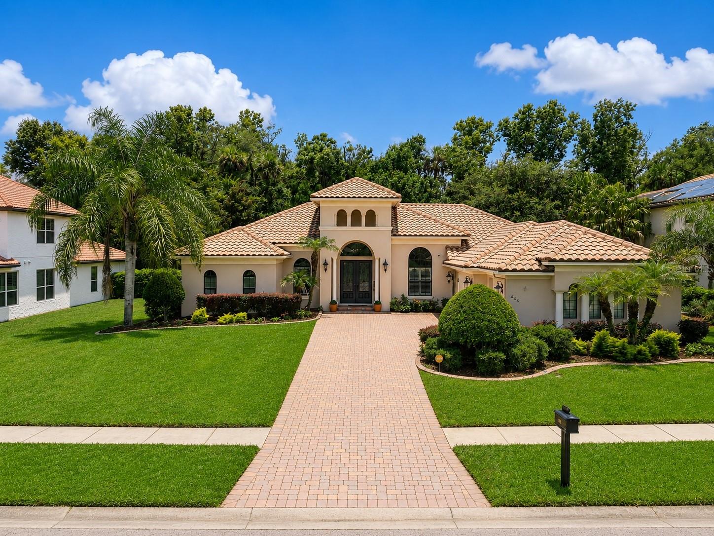 Timeless architecture, exceptional craftsmanship, and effortless elegance come together in this remarkable custom-built residence nestled within one of Oviedo's most sought-after gated communities. Perfectly positioned on a private homesite with wooded views and no rear neighbors, this home offers the rare combination of luxury, privacy, and everyday comfort in an A+ school district. A grand entryway welcomes you inside, where soaring ceilings, refined architectural details, and an abundance of natural light create a sense of sophistication. Designed with both entertaining and everyday living in mind, the open-concept floorplan flows seamlessly from one appointed space to the next. At the heart of the home, the chef's kitchen is as functional as it is stunning, featuring solid wood custom cabinetry, granite countertops, premium stainless steel appliances, an expansive breakfast bar, a spacious walk-in pantry, and a separate butler's pantry that makes hosting effortless. Every detail has been carefully considered, from the custom built-ins to the thoughtfully curated modern fixtures that bring warmth, texture, and timeless sophistication to every room. A dedicated custom wine cellar offers the perfect place to showcase your collection and creates an elegant focal point rarely found in homes at this price point. Whether hosting intimate dinner parties or larger gatherings, every detail has been thoughtfully designed for elevated living. The designed split floorplan provides exceptional privacy, with the luxurious primary suite tucked away as its own private retreat. Complete with a relaxing garden tub, spacious walk-in shower, generous walk-in closet, and spa-inspired atmosphere, it's a place designed to unwind after a long day. Step outside to discover one of the home's most impressive features; a massive screened lanai finished with brick pavers, creating an exceptional outdoor living space that overlooks a tranquil wooded backdrop. Professional grade artificial turf provides year-round beauty with virtually no maintenance, allowing you to enjoy the landscape without the upkeep while preserving complete backyard privacy. Beyond its timeless design, this residence has been meticulously updated for years of worry-free ownership, including a new AC system (2025), new water heater (2025), new security system, recently sealed pavers, and mature professional landscaping that enhances the home's outstanding curb appeal. A durable terracotta tile roof, an oversized three-car garage, and exceptional attention to detail throughout speak to the quality craftsmanship and timeless design that define this remarkable home. Located within one of Oviedo's premier gated neighborhoods and zoned for Seminole County's top-rated schools, you'll enjoy convenient access to Oviedo on the Park, the 417 Expressway, UCF, Orlando International Airport, Downtown Orlando, Central Florida's world-renowned attractions, including Disney, Universal Studios, the Space Coast, and the area's beautiful east coast beaches. Nearby Cross Seminole Trail, Central Winds Park, championship golf courses, upscale dining, boutique shopping, and countless recreational opportunities complete the lifestyle this exceptional location provides. This is more than a home, it's an opportunity to experience refined Florida living at its finest. Schedule your private showing today and discover why this extraordinary residence is one of Oviedo's most exceptional offerings. This is it!