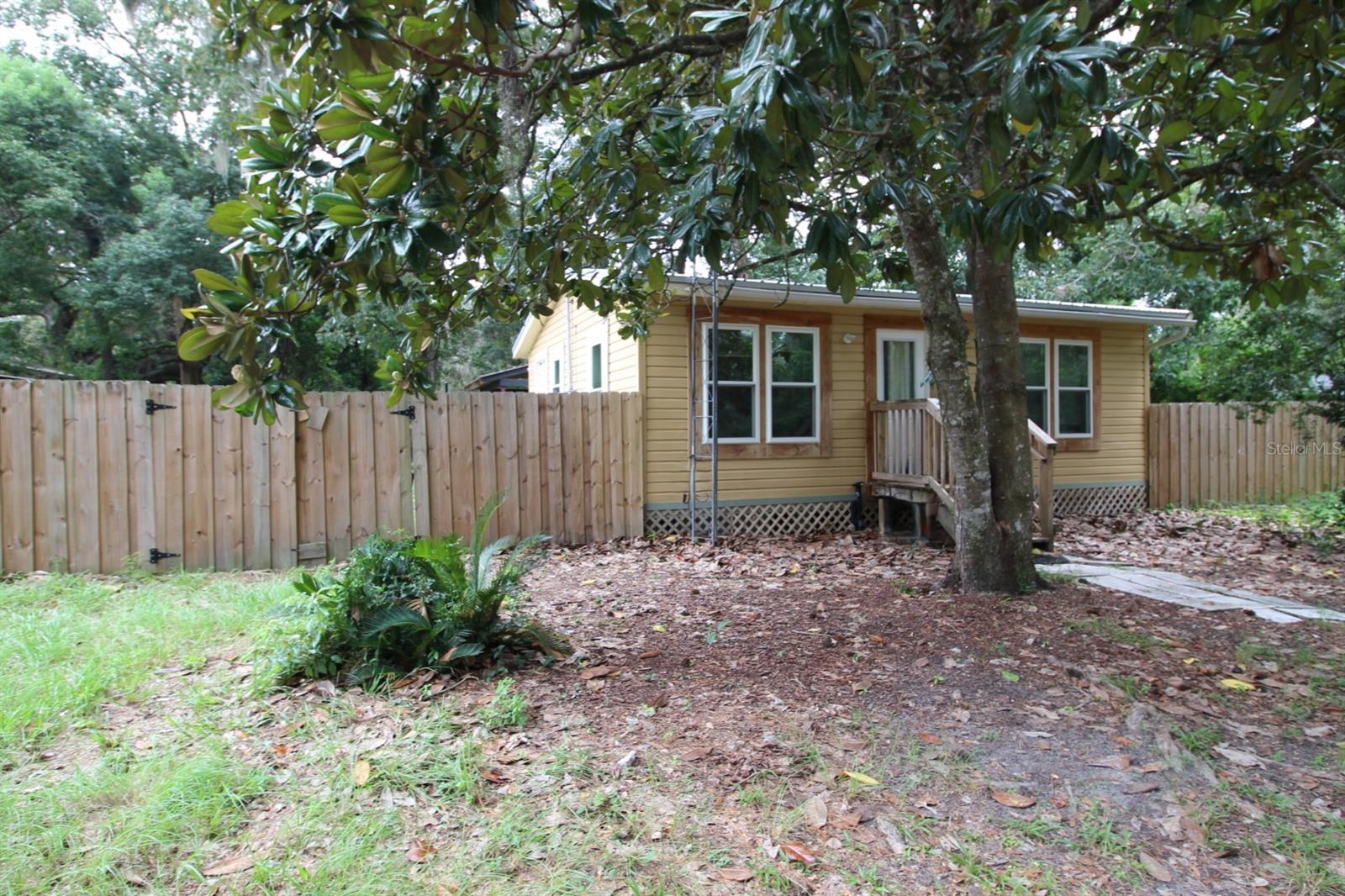 Tucked away on a quiet street in the heart of a charming small town, this cozy home offers the perfect blend of comfort and convenience. The inviting living space features an open layout, with plenty of natural light that makes it feel bright and airy. The kitchen is efficiently designed, making meal prep a breeze. Step outside to discover a private, fully fenced backyard—an ideal spot for recreation and relaxation. Cross fencing offers an opportunity to grow your own produce, a brood of chickens, and other creatures you want to include in your mini farm.  A large covered patio makes for a great entertainment space. A 10x20 loft barn is ready for utility hook ups and hobby benches. Just a short walk to local parks, public library, and weekly Farmers Market. Easy 20-25 minute commute to Gainesville, UF, UF Health, VA Hospital, Butler Plaza, and Celebration Pointe. 40 minutes to Gulf fishing in Cedar Key. Home should qualify for conventional, FHA, & USDA