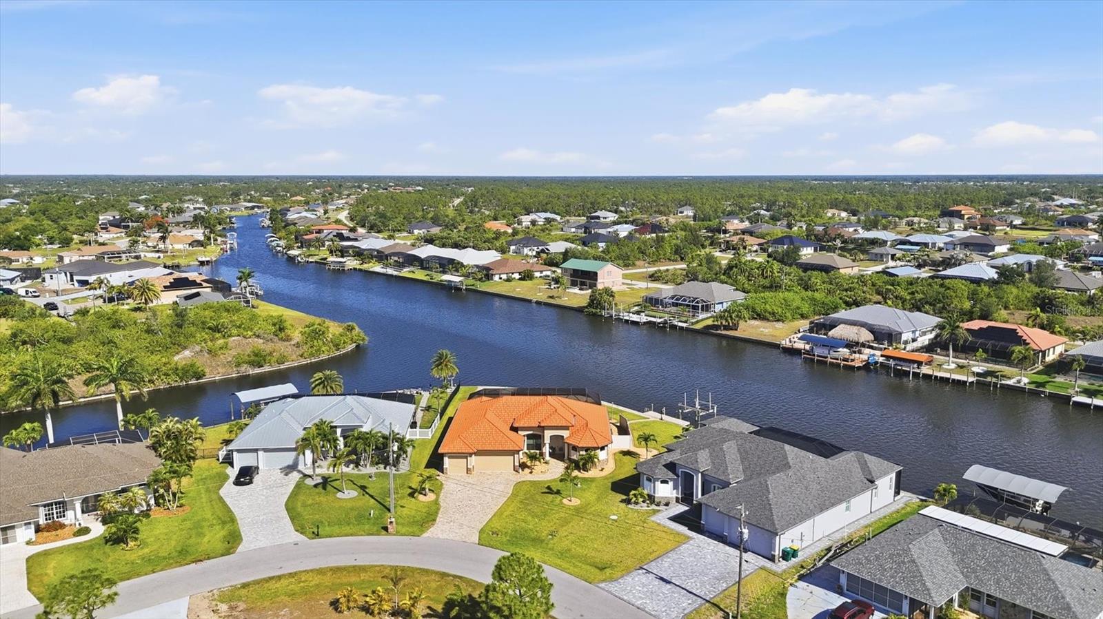 Located on a premium waterfront lot in South Gulf Cove, this meticulously maintained home is packed with upgrades and desirable features including impact windows and doors, granite countertops throughout, a heated pool, frameless lanai screen (2023), whole-house generator, 500-gallon propane tank, new roof (2023), water filtration system, a mist away system, hardwired security cameras, irrigation system (reclaim water), gutters, and a waterfront fire pit to name just a few. This tip lot (17,068 SqFt) offers panoramic water views of intersecting canals integrated throughout the interior and exterior living spaces. Enjoy stunning sunsets overlooking the widest section of the Zephyr waterway with 163 feet of seawall waterfront. Bring your boat, or plan for a future purchase, with your private dock featuring a 10,000-pound lift plus electric and water already in place. As you arrive at this waterfront oasis, you’ll immediately notice the curb appeal from the wide paver driveway, stonework accents, front porch, and decorative glass double-door entry. Once inside, your attention is instantly drawn to the expansive water views and your outdoor sanctuary visible through multiple sliding glass doors. The zero-corner pocket slider creates a seamless extension into the expansive screened lanai. Throughout the home you’ll find tile flooring, high ceilings, crown molding, recessed lighting, and rounded corners. The living room features a backlit entertainment wall with an electric fireplace, plus a double tray ceiling at 14’2”. Off the living room is the office/den with French doors. The kitchen open to the main living and dining areas features an abundant of soft-close wood cabinets with pullouts, two-tone granite countertops, dark stainless appliances, pendant lighting, backsplash, built-in pantry, and an additional 10-foot coffee bar opposite the oversized island. The primary and guest bedrooms are on opposite sides of the home providing ample space and privacy for all. The primary suite offers a double tray ceiling, lanai access, two walk-in closets with built-ins, additional storage, freestanding soaking tub, dual sinks, oversize walk-in shower, and of course water views. A pocket door closes off the guest quarters, which includes two bedrooms, one with lanai access, and a bathroom that doubles as a pool bath. The laundry room provides extra storage and a sink. The three-car garage accommodates extended-cab vehicles and features an epoxy floor, two side door entrances, a separate storage room, with both the garage and covered lanai having antic insulation. The spacious paver outdoor living area offers both covered and sun-exposed spaces within the screened lanai, creating the perfect setting to enjoy the Florida lifestyle. Whether you’re dining al fresco, entertaining family and friends, watching the game, lounging poolside, or enjoying your morning coffee while watching the wildlife and boaters, this home was truly designed for waterfront living. Step outside the lanai to play cornhole, throw the ball around, relax by the fire pit at the water’s edge or cruise around the waterways while taking in the sunset. An electric hurricane screen on the covered lanai provides added storage protection while out of town. Head out to the beach to change your scenery, visit one of the many local waterfront restaurants, or stop by Publix to pick up supplies, all of which are a short drive away from your Florida waterfront retreat. No CDD or required HOA fee.