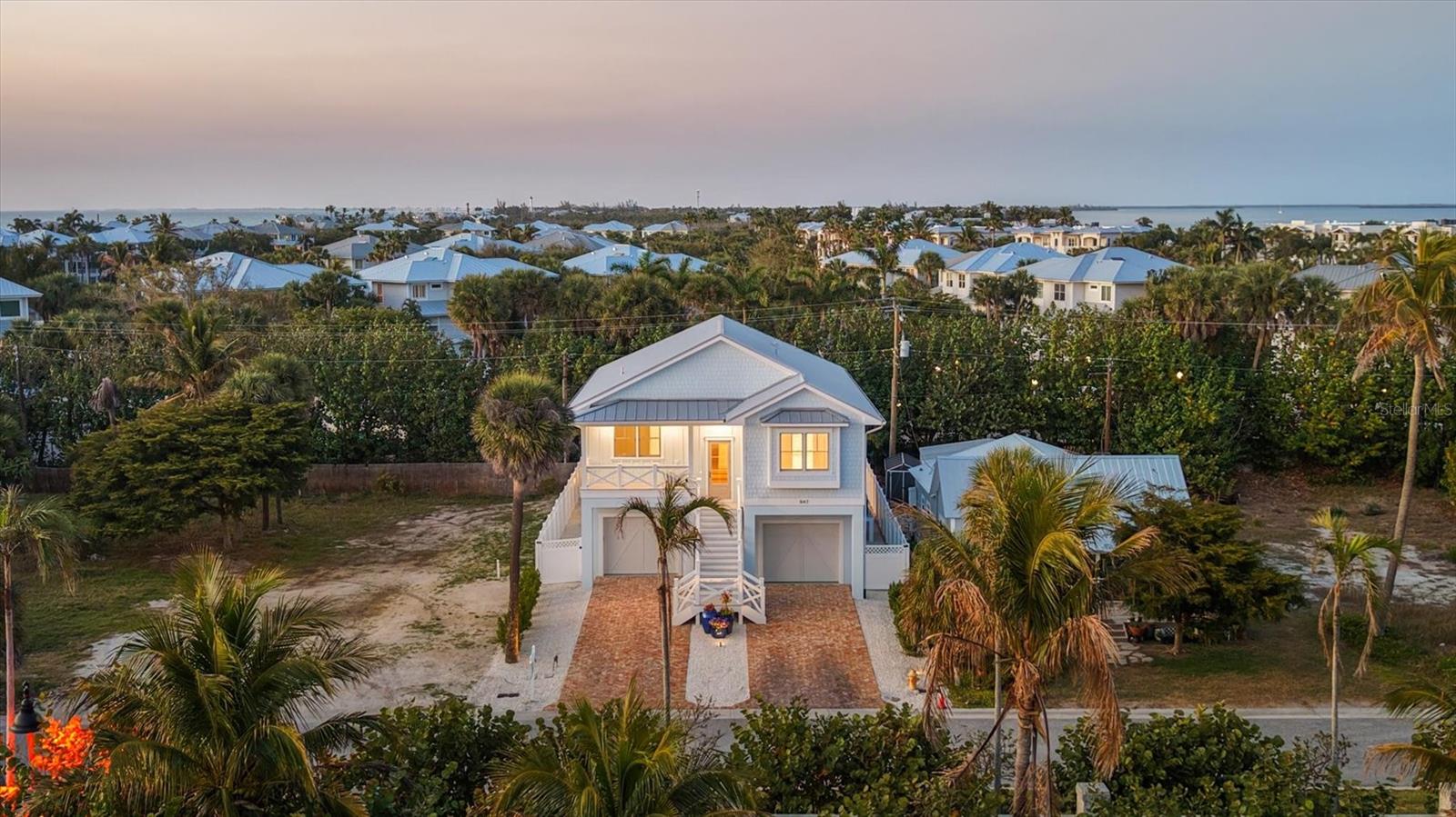 Custom new construction coastal cottage located on the southernmost point of sought-after Boca Grande — just steps from the pristine beaches and emerald-green waters of Gasparilla Island State Park.
This thoughtfully designed residence features 5 bedrooms, 4.5 bathrooms, and over 3,000 square feet of living space, highlighted by 13-foot vaulted tongue-and-groove ceilings throughout the main living areas. Built with exceptional quality and efficiency, the home includes spray foam insulation, Andersen impact windows and front door, durable Hardie board siding, and Azek trim for long-lasting coastal performance and peace of mind.
The gourmet kitchen is beautifully appointed with a gas Thermador range, panel-ready appliances, and cabinetry offering abundant storage — ideal for both everyday living and entertaining.
Each bedroom on the main living level features vaulted tongue-and-groove ceilings, walk-in closets, and private en suites, creating a true retreat for family and guests alike. The 13-foot board-and-batten vaulted hallway serves as a stunning architectural focal point and a statement of craftsmanship.
The first floor offers a full-over-full bunk room, a guest bedroom, and a spacious family room, providing flexible living and gathering spaces.
Step outside to your shellstone pool deck, where you’ll enjoy a resort-style pool with a waterfall and linear fire feature, all overlooking the outdoor living area complete with a custom stone kitchen — perfect for sunset dinners and coastal entertaining.
This tastefully designed coastal cottage blends refined luxury with relaxed island living — just steps from the beach and breathtaking sunsets.
Request your private showing today