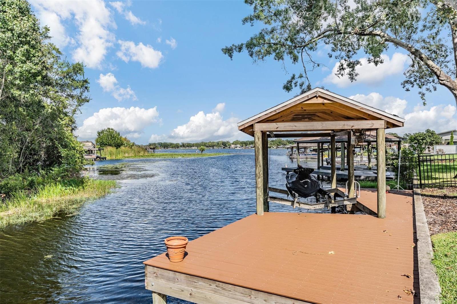 One or more photo(s) has been virtually staged. Step inside and experience the transformation! ALL INTERIOR WALLS HAVE JUST BEEN REPAINTED IN A NEUTRAL COLOR PALETTE!!  Floorplan is open and bright! Welcome to this one-of-a-kind waterfront estate in the highly sought-after Lake Padgett Estates community, offering deeded water rights, two parcels that extend directly into the 95 acre ski lake, East Lake...a rare ownership opportunity for both land and water rights. Bring you boat and jet skis - East Lake is a 95 acre ski lake! The home has been UPDATED for peace of mind with a NEW INTERIOR PAINT, NEW ROOF, 3 YR OLD AC, 2 YR OLD WATER HEATER, NEW SCREENING on the enclosure, and a rebuilt DOCK WITH TREX DECKING AND NEW BOAT DOCK ROOF. Parking and storage are a dream with an attached two car garage, a DETACHED GARAGE WITH ONE CAR GARGE with a soaring 9 FOOT DOOR, plus an additional GOLF CART GARAGE tucked behind the detached bay. Step through the front door into more than 3,300 square feet of heated living space, where TALL CEILINGS and EXPANSIVE WINDOWS create a bright and welcoming atmosphere. The main home features four bedrooms and three bathrooms, including a private upstairs bedroom with its own bath, perfect for guests or multi-generational living. The kitchen is the centerpiece of the home, offering rich wood cabinetry, granite countertops, a central island, NEWER STAINLESS APPLIANCES, a built in wine rack, and plenty of counter space. From here, the floorplan flows easily to both casual and formal living spaces, all oriented toward the water. The primary suite is spacious and serene, with crown molding, a spa like bath, and a custom built walk in closet. Secondary bedrooms provide flexibility for family and guests. Plus a  SEPARATE OFFICE/DEN downstairs. Outdoor living is where this estate truly shines. The screened lanai opens to a RESORT STYLE HEATED POOL AND SPA with ROCK WATERFALL and lush landscaping. The OUTDOOR KITCHEN is fully equipped for gatherings, featuring a built in GRILL,  a large GREEN EGG SMOKER, FIREPLACE, MINI FRIDGE, AND SINK with running water. ABOVE GARAGE, ABOVE LANAI, accessible only by a PRIVATE EXTERIOR STAIRWAY, is an ADDITIONAL 500+ SF BONUS ROOM, complemented by a SECOND STORY BALCONY DECK for elevated entertaining. This is a versatile space ideal for a game room, poker lounge, theater, or second office with its own mini-split AC. Life here means direct access to Lake Padgett’s three lakes, well-known for boating, skiing, and fishing, access to all community parks and playgrounds, being an eqestrian community, if you have a horse you'll have access to the stalls, along with the privacy and space of a rare waterfront estate. This home blends thoughtful updates, rare land and water rights, flexible living spaces, and true resort-style outdoor amenities, making it an incomparable offering in Land O’ Lakes. A few minuties down the street are a public library and Land O Lakes Community Center with ball fields, park, pool, tennis, indoor bascketball, and variety of classes!  ASK FOR THE  FEATURE SHEET OF UPDATES! Be sure to view the 3D tour and video made for this exceptional lake front property! Now is the time to purchase this lakefront paradise!