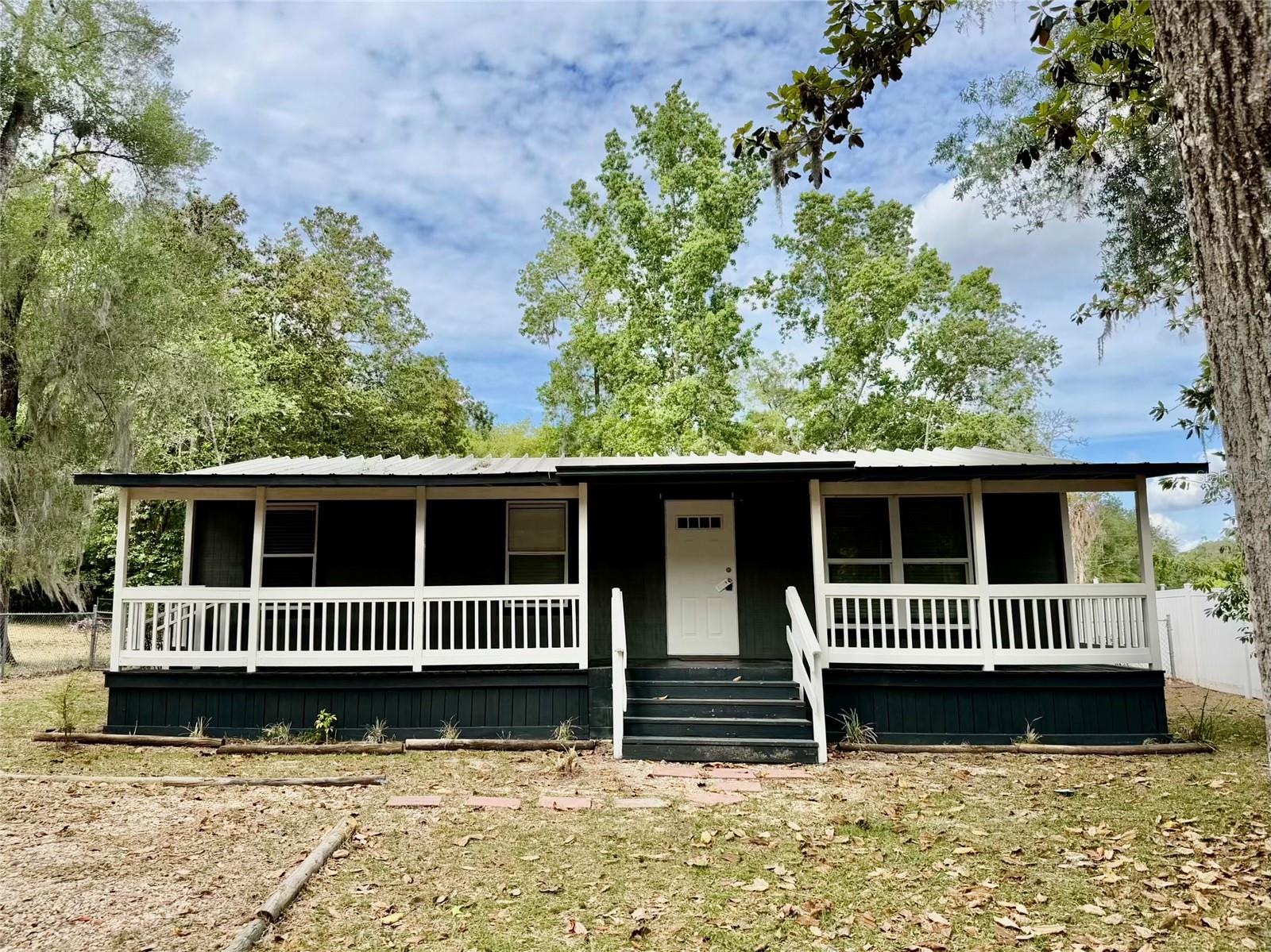 Welcome to this charming 3 bedroom, 1 bath home in the heart of Bushnell, where country living meets modern comfort. Recently remodeled, this inviting home features stylish laminate flooring throughout, fresh interior paint, and a brand-new refrigerator and range, making it truly move-in ready. The bright and airy living room is highlighted by large, picturesque windows that fill the space with beautiful natural sunlight, creating a warm and welcoming atmosphere. Step outside and enjoy the best of Florida living with a covered front porch that spans the entire length of the home, perfect for relaxing mornings or evening unwinding. Out back, a huge screened-in covered porch offers extended living space ideal for entertaining or enjoying the peaceful surroundings year-round. This property also offers plenty of practical features, including abundant storage on the back patio, a spacious storage shed, and a durable metal roof. The fully fenced backyard provides privacy and includes mature fruit trees, adding both beauty and functionality to your outdoor space. Nature lovers will appreciate the home’s close proximity to the scenic Withlacoochee River and the expansive Withlacoochee State Forest, where you can enjoy fishing, hiking, and miles of picturesque trails. Whether you’re searching for a full-time residence or a relaxing weekend getaway, this property offers comfort, charm, and a tranquil setting you’ll love coming home to. Seller financing is available for qualified buyers. Call to schedule your private showing today.