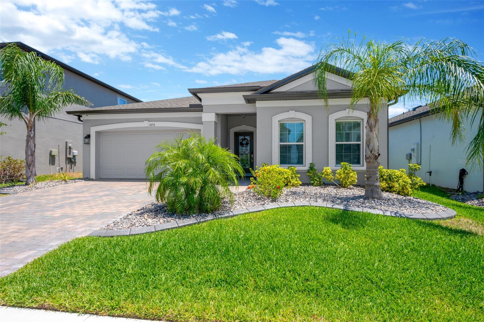 Better than new and impeccably maintained, this stunning home in the highly desirable Berry Bay community is loaded with over $30,000 in premium upgrades and is truly move-in ready! This beautifully designed 3-bedroom, 2-bath home offers an open-concept floor plan with high  ceilings, luxury wood-look vinyl plank flooring, upgraded baseboards, and abundant natural light throughout. The gourmet kitchen is the heart of the home, featuring quartz countertops, a large island, stainless steel appliances, upgraded cabinetry with crown molding, and thoughtful custom storage. The spacious primary suite offers a tray ceiling, custom walk-in closet, dual vanities, a large walk-in shower, and a relaxing soaking tub. Enjoy seamless indoor-outdoor living on the screened lanai with a roll-down privacy shade, overlooking professionally enhanced landscaping with decorative rock borders, over 10 newly planted palm trees, and a sealed paver driveway. Additional upgrades include a whole-home sound system, security cameras, smart home features, custom closet systems, laundry room cabinetry, garage ceiling storage, and more. Berry Bay offers resort-style amenities including a pool, clubhouse, playgrounds, pickleball and basketball courts, all with a low HOA. Conveniently located near I-75, with easy access to Tampa, St. Petersburg, Sarasota, and the Gulf beaches. Skip the wait and extra expense of new construction—this exceptional home already has it all!