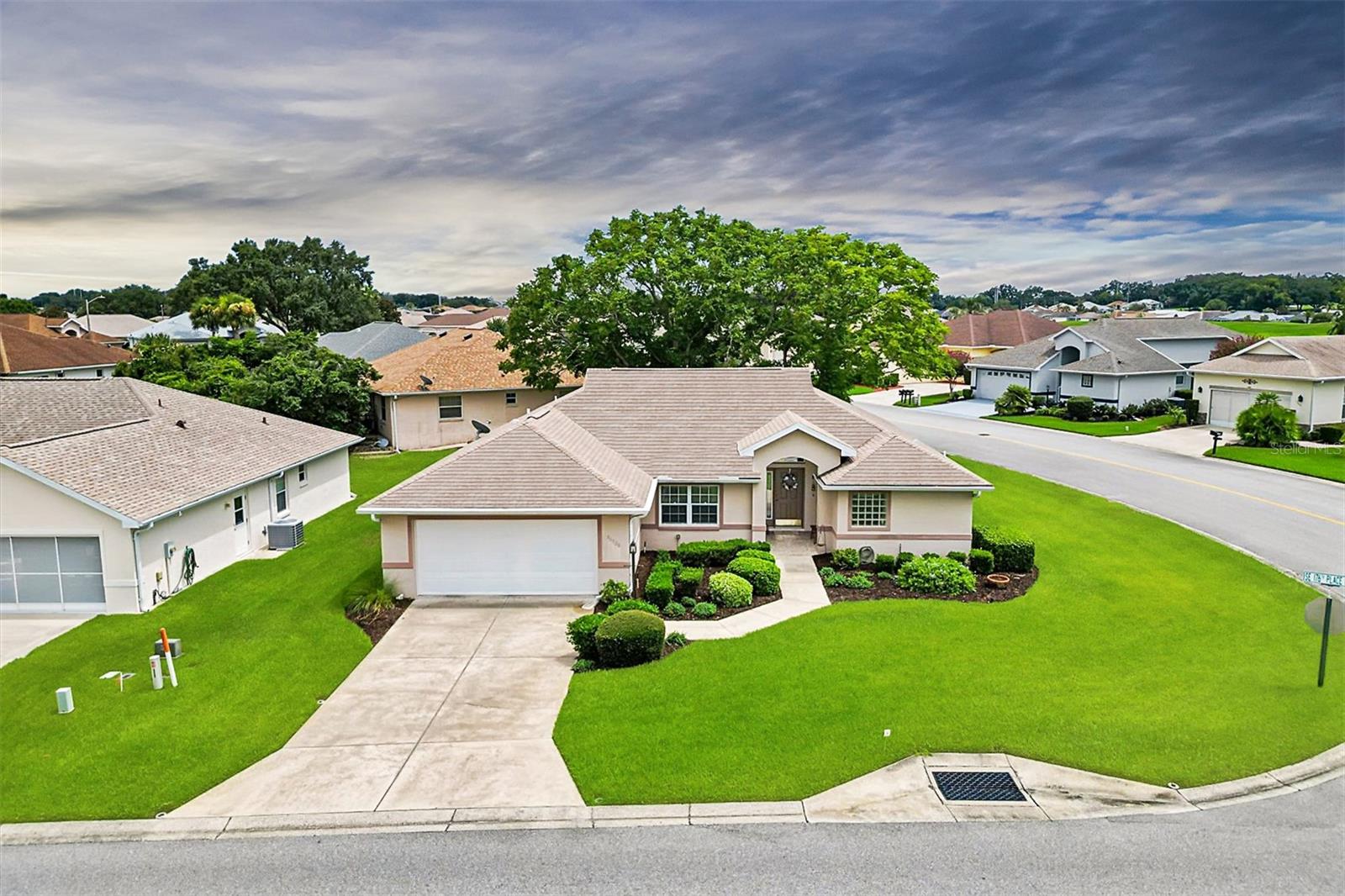 Welcome to your own slice of paradise in the highly sought after 55+ Gated Golf Community of STONECREST, perfectly situated adjacent to THE VILLAGES, Florida, where golf cart access makes everyday living effortless. This lovingly maintained, one owner home offers 3 Bedrooms, 2 Bathrooms, and a bright Florida room with NEW WINDOWS, creating the perfect setting to relax, entertain, or simply enjoy the peaceful Florida lifestyle.  Designed with comfort and openness in mind, the home Features soaring VAULTED CEILINGS in the Kitchen, Living room, and Primary Bedroom, while a thoughtful 3 Foot extension across the back of the home provides even more spacious living. Beautiful HARDWOOD Flooring enhances the Living room, complemented by TILE throughout all wet areas for easy maintenance. The remodeled Kitchen is sure to impress with elegant QUARTZ countertops and newer stainless steel appliances, with the exception of the range. Major updates include a ~*~*~ 2020 ROOF and a 2013 HVAC system ~*~*~.  Situated on a desirable corner lot, the backyard is graced with mature shade trees that create a tranquil retreat where you can enjoy your morning coffee, watch the birds, or unwind after a day on the golf course.  Life in Stonecrest is about so much more than owning a beautiful home, it's about embracing an active, carefree lifestyle that feels like paradise every day. Residents enjoy a championship 18 hole golf course, four swimming pools, a state-of-the-art fitness center, pickleball and tennis courts, dog park, softball, bocce ball, and countless social clubs and activities. Meet friends for dinner at the community restaurant, enjoy live entertainment, dance the night away, or take your golf cart to nearby shopping, restaurants, medical facilities, and all the excitement of The Villages. Whether you're looking for relaxation, recreation, or a vibrant social life, Stonecrest offers the perfect blend of luxury, convenience, and resort-style living. Once you experience this exceptional community, you'll understand why so many proudly call it home.