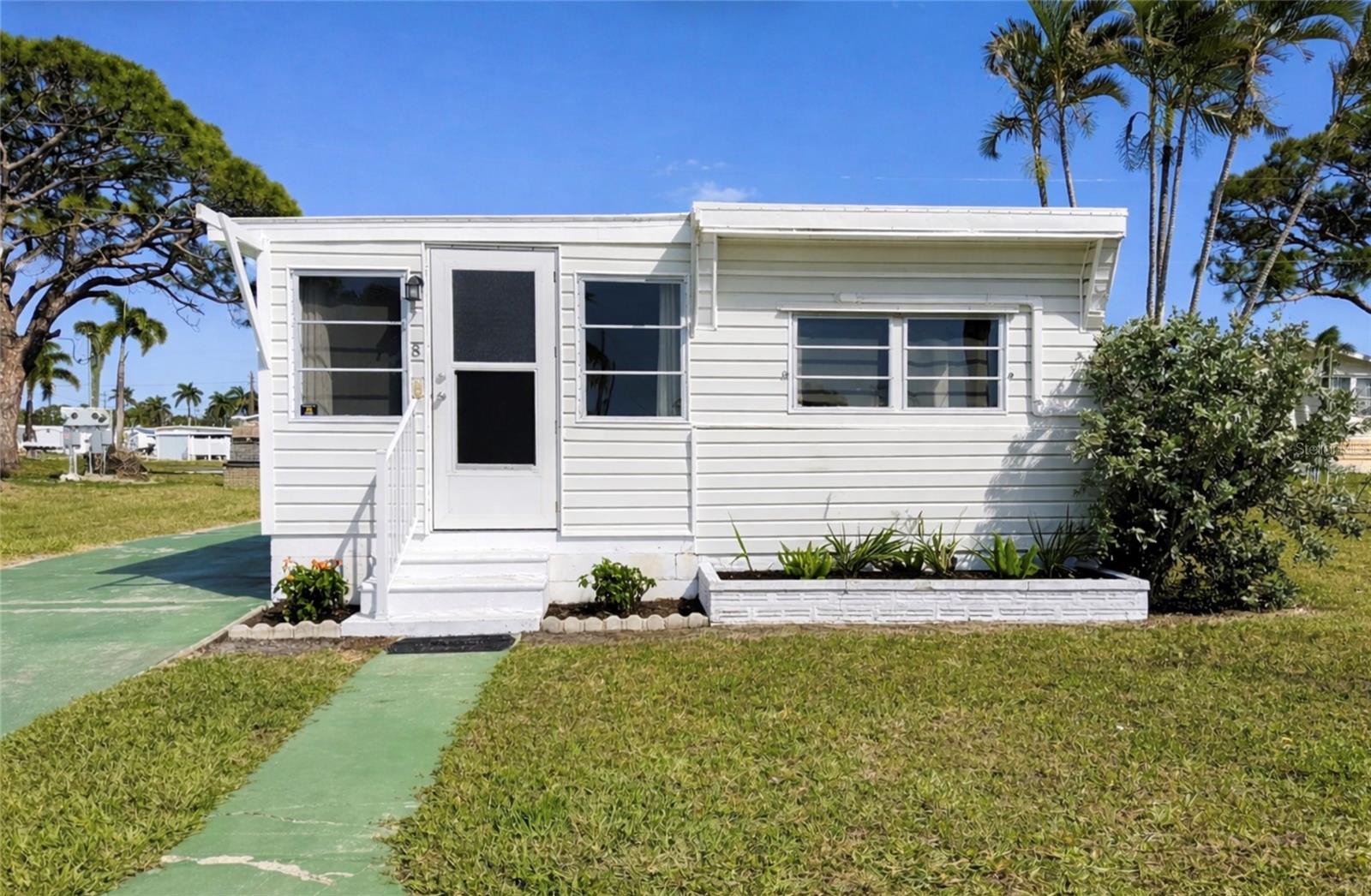What a view!
Wake up each day to stunning water views right from your living room, or step outside your front door and take it all in. This is the kind of setting that makes Paradise Bay so special.
This beautifully renovated 2-bedroom, 1-bath home offers a light and inviting feel, with thoughtful updates throughout that make it truly move-in ready. The kitchen has been designed with both style and function in mind, featuring cabinetry tailored for sheet pans and cutting boards, along with convenient pull-out shelving for easy access and storage. The primary bedroom even includes built-in under-bed storage with a lift-up frame—maximizing space without sacrificing comfort.
Whether you're relaxing inside or soaking in the scenery outside, this home is all about embracing the Florida lifestyle.
Located in the highly desirable Paradise Bay, a 55+ co-op community, residents enjoy a variety of amenities along with a low HOA fee—making it an ideal option for full-time living or a seasonal retreat. For boating enthusiasts, homes with a slab driveway allow for boat parking, and residents have access to a community boat launch. Boat slips may also be available through the community manager for an additional fee.
Conveniently situated near shopping, dining, and just a short drive to Anna Maria Island—famous for its turquoise waters and sugar-white sand beaches—you’ll have everything you need within reach.
If you’ve been waiting for a home with a view, this is the one.
