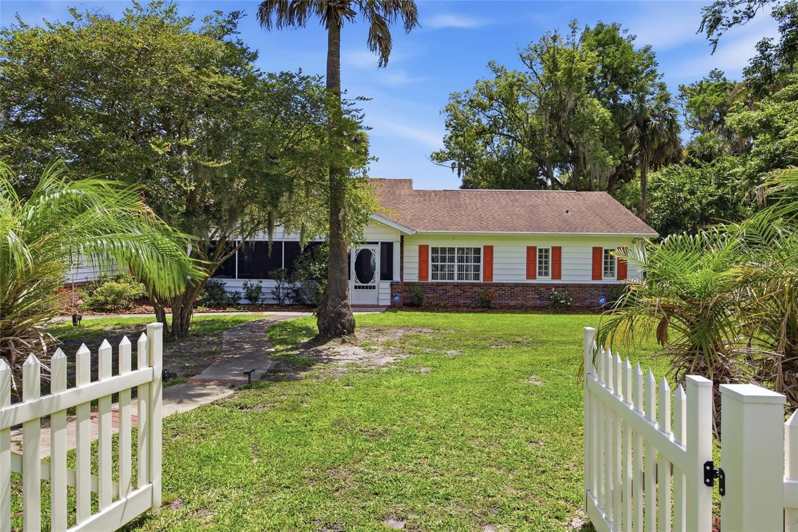 Seller is open to seller financing with a 25% + downpayment & a shorter balloon period. Experience lakefront living from this beautifully renovated waterfront retreat surrounded by mature palms, tropical landscaping, and panoramic views of Lake Griffin on the renowned Harris Chain of Lakes and access to the Atlantic Ocean. Positioned on an 1.08 acre lot with approximately 125 feet of direct waterfront frontage and neighboring the serene 40-acre Bourlay Historic Nature Park. No fixed bridges and No flooding. This remarkable property offers an unmatched blend of privacy, natural beauty, and timeless elegance with no HOA restrictions. Over 500 feet of charming picket fencing frame the property while mature landscaping creates a welcoming and picturesque setting. A spacious screened front porch invites you into the home. Inside, soaring 12-foot vaulted ceilings, wide-plank Tigerwood flooring, crown molding, plantation shutters, and expansive French doors create a warm yet refined atmosphere throughout the residence. At the heart of the home is a stunning open-concept living area designed to maximize the spectacular waterfront views. The expansive great room features a gas fireplace and an impressive wall of windows that fill the home with natural light while showcasing the sparkling lake beyond. Seamlessly connected to the living space is the gourmet style kitchen, thoughtfully designed with rich custom wood cabinetry, granite countertops, built-in food warmer, easy pull-out cabinet drawers with lazy Susans, stainless steel appliances, and a large center island ideal for entertaining or meal prepping. The primary suite serves as a peaceful private retreat with tranquil water views, its own gas fireplace, French doors leading directly to the screened lanai, and a spa-inspired en-suite bath featuring an oversized soaking tub, and a separate walk-in shower. Each additional bedroom offers the comfort & convenience of a private bathroom, creating ideal accommodations for family or guests. Additional flex space provides versatile living options such as a den/bedroom. Outdoor living is equally impressive and perfectly suited for enjoying Florida’s year-round lifestyle. The expansive screened lanai features a wet bar and opens effortlessly to over 630 square feet of paved patio space, complete with a natural gas hookup for grilling, an infrared spa that seats 4, and outdoor entertaining. The oversized backyard offers endless possibilities, including ample room for the future pool of your dreams, all while overlooking the tranquil water and sunset views. Additional parking space that's prefect for your boat or RV with completely fenced front yard. This exceptionally maintained residence also offers the convenience and peace of mind of city water, sewer, natural gas service, a newer roof, and a generator. Boating enthusiasts will appreciate direct access to the Harris Chain of Lakes, with Bass fishing, waterfront dining, cruising through interconnected lakes, and exploring nearby charming lakefront towns. Ideally located just minutes from historic downtown Leesburg, The Villages, Leesburg International Airport, shopping, dining, and entertainment.