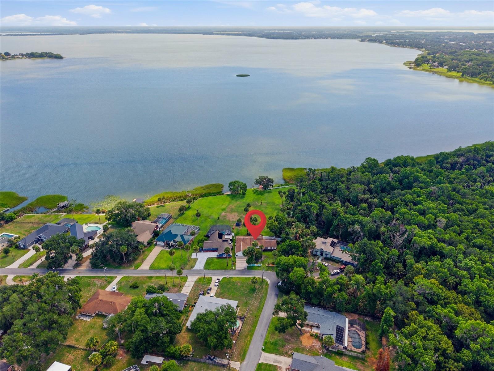 Experience extraordinary lakefront living from this beautifully renovated waterfront retreat surrounded by towering mature palms, lush tropical landscaping, and breathtaking panoramic views of Lake Griffin on the renowned Harris Chain of Lakes. Perfectly positioned on an 1.08 acre lot with approximately 125 feet of direct waterfront frontage and neighboring the serene 40-acre Bourlay Historic Nature Park. This remarkable property offers an unmatched blend of privacy, natural beauty, and timeless elegance with no HOA restrictions. From the moment you arrive, the home’s impressive curb appeal and meticulous attention to detail are immediately evident. Over 500 feet of charming picket fencing frame the property while mature landscaping creates a welcoming and picturesque setting. A spacious screened front porch invites you into an interior designed to capture both comfort and sophistication. Inside, soaring 12-foot vaulted ceilings, wide-plank Tigerwood flooring, crown molding, plantation shutters, and expansive French doors create a warm yet refined atmosphere throughout the residence.
At the heart of the home is a stunning open-concept living area designed to maximize the spectacular waterfront views. The expansive great room features a gas fireplace and an impressive wall of windows that fill the home with natural light while showcasing the sparkling lake beyond. Seamlessly connected to the living space is the gourmet style kitchen, thoughtfully designed with rich custom wood cabinetry, granite countertops, built-in food warmer, easy pull-out cabinet drawers with lazy Susans, stainless steel appliances, and a large center island ideal for entertaining or meal prepping. Every detail of the kitchen was carefully selected to combine beauty & functionality while embracing the home’s exceptional lakefront setting. The primary suite serves as a peaceful private retreat with tranquil water views, its own gas fireplace, French doors leading directly to the screened lanai, and a spa-inspired en-suite bath featuring an oversized soaking tub, separate walk-in shower, and generous space designed for relaxation. Each additional bedroom offers the comfort & convenience of a private bathroom, creating ideal accommodations for family or guests. Additional flex space provides versatile living options such as a den/bedroom. Outdoor living is equally impressive and perfectly suited for enjoying Florida’s year-round lifestyle. The expansive screened lanai features a wet bar and opens effortlessly to over 630 square feet of paved patio space, complete with a natural gas hookup for grilling, an infrared spa that seats 4, and outdoor entertaining. The oversized backyard offers endless possibilities, including ample room for the future pool of your dreams, all while overlooking the tranquil water and unforgettable sunset views. Additional parking space that's prefect for your boat or RV with completely fenced front yard. This exceptionally maintained residence also offers the convenience and peace of mind of city water, sewer, natural gas service, a newer roof, and a generator. Boating enthusiasts will appreciate direct access to the Harris Chain of Lakes, allowing endless opportunities for fishing, waterfront dining, cruising through interconnected lakes, and exploring nearby charming lakefront towns. Ideally located just minutes from historic downtown Leesburg, The Villages, Leesburg International Airport, shopping, dining, and entertainment.