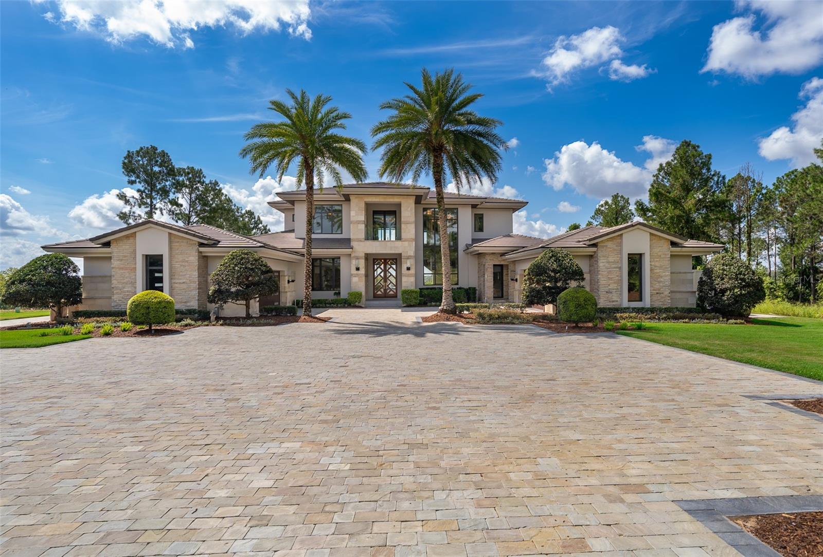 5 Bedrooms | 5 Full Baths | 3 Half Baths | Lake front-Private Pool | 4-Car Climate-Controlled Garage

Experience refined living in this custom-built, lakefront ( Lake Apopka) estate in the exclusive, guard-gated community of Bella Collina. Designed for both grand entertaining and everyday luxury, the open-concept main living area features soaring ceilings, a stone fireplace wall, and expansive sliding glass doors that blur the line between indoor and outdoor living. The chef’s kitchen is a true showpiece with a waterfall-edge quartz island, Thermador appliances, custom cabinetry, and a spacious walk-in pantry—perfect for hosting gatherings or preparing intimate meals.

The main level boasts a custom-built bar with dual wine refrigerators, an entertainment lounge that flows seamlessly to the lanai, a home office, a guest suite with en-suite bath, and two designer guest baths. The luxurious primary suite is a private retreat, featuring a stone fireplace, morning bar with Thermador coffee system, spa-style bath, and private lanai with fireplace—ideal for unwinding while overlooking the serene pool and landscaped grounds.

Upstairs offers three additional en-suite bedrooms boasting balcony access, perfect for enjoying morning coffee or evening sunsets, a bonus/media room, and half bath, ensuring comfort and privacy for family and guests alike. Outdoors, the home transforms into a resort-inspired retreat with a fully equipped summer kitchen, covered lounge and dining areas, and multiple spaces designed for both relaxation and entertainment. Host sunset gatherings poolside, enjoy weekend brunch under the wood-paneled lanai, play golf in your private putting green with bunkers from an elevated 70-yard (approx.) tee or take in the views while lounging by the sparkling pool framed by lush landscaping.

Premium upgrades include a Crestron Home Automation System which allows the control of lights, shades, temperature, music, security and more from a single platform, elevator, built-in speaker system, water filtration, and a climate-controlled 4-car garage with utility area. Located within a short distance to the amenity-rich setting of Bella Collina, featuring a Nick Faldo Championship golf course, a luxurious spa, Har-Tru tennis courts, pickleball courts, clubhouse, outdoor pool complex, cutting-edge fitness center with complimentary fitness classes, lake views and monthly culinary and/or wine events. Don’t miss the opportunity to own this one-of-a-kind luxury retreat in Central Florida’s premier private community.