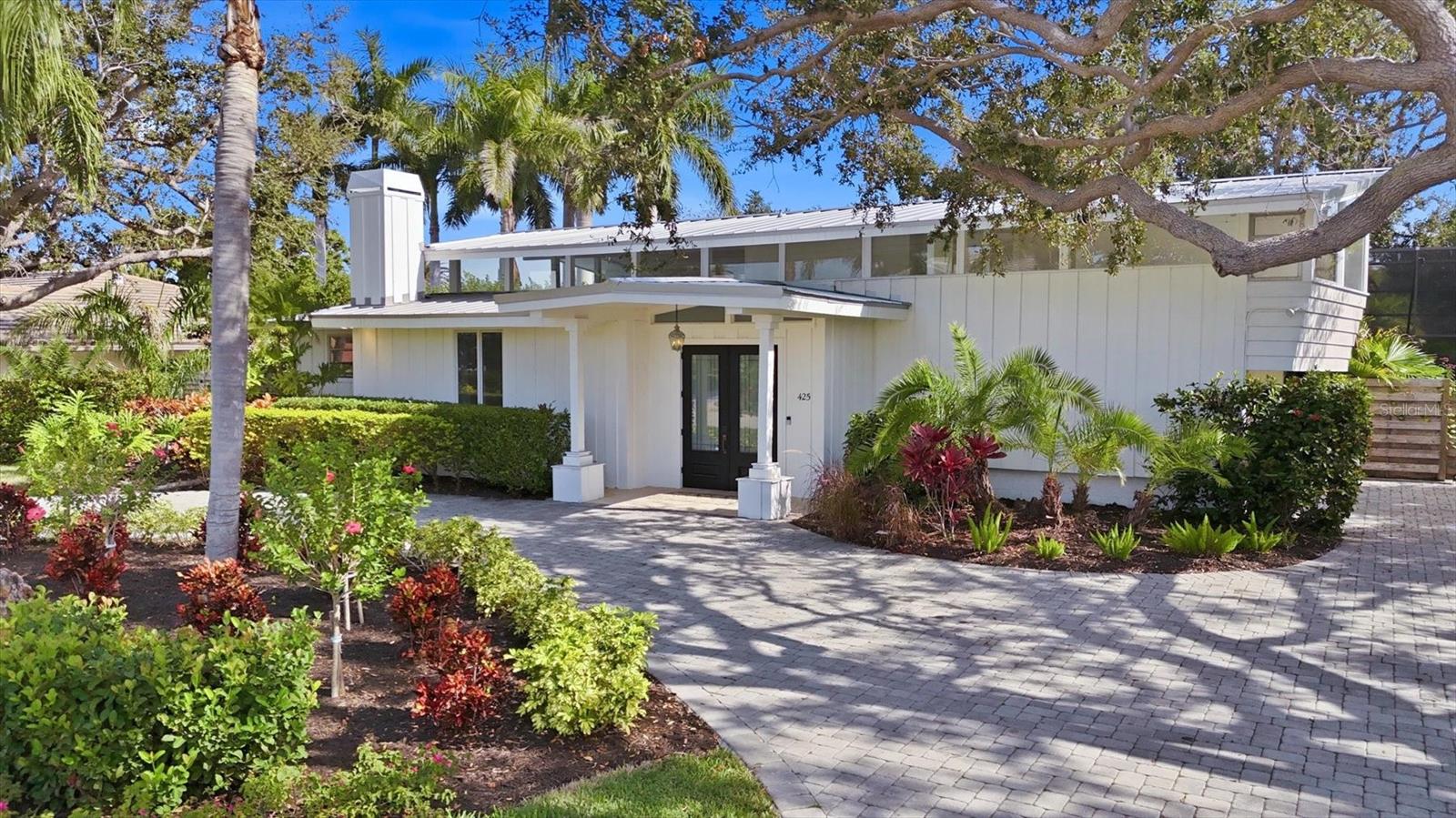 One or more photo(s) has been virtually staged. 425 Partridge Circle is a rare Mid-century Modern gem in the heart of Bird Key, originally designed in the 1960s by noted architect John M. Crowell. Set on a lush garden lot surrounded by mature tropical landscaping, this home blends iconic architectural features with thoughtful modern updates. The residence offers an open floor plan enhanced by expansive windows that invite in beautiful natural light and frame the vibrant tropical landscape and pool area. The striking coral-mantled woodburning/gas fireplace, high ceilings, stone countertops, Viking gas range with vent hood, and wine refrigerator all contribute to the home’s refined character. The two-story pool cage further elevates the setting, creating a dramatic sense of space and a completely private outdoor oasis. The main-floor primary suite features a spacious bathroom with a private outdoor shower, along with two closets—one a generous walk-in and the other a built-in wardrobe. Upstairs, a secluded guest suite offers ideal privacy and is complemented by a versatile flex room that can serve as an additional bedroom, office, or media room, along with its own full bath. Outdoors, the property transforms into a resort-like retreat with a heated saltwater pool designed by Lucas Lagoons, complete with a waterfall, spa, and grotto elements. The screened-in pool area includes an outdoor kitchen and shower, perfect for year-round enjoyment. The landscaping and irrigation system have been fully renewed, including a dedicated irrigation well. The metal roof was installed in 2024 and pool equipment replaced in 2023. In addition to its architectural significance, the property offers exceptional flexibility—whether you choose to further enhance this mid-century modern residence or start fresh and build a custom home from the ground up you have the freedom to bring your vision to life without limitation. Located just minutes from Lido Beach, St. Armands Circle, downtown Sarasota, and SRQ Airport, and within close proximity to the Bird Key Yacht Club, this home offers an exceptional combination of architectural pedigree, modern comfort, and an unparalleled island lifestyle. This is a rare opportunity to own a piece of Sarasota’s design history in one of its most sought-after neighborhoods.