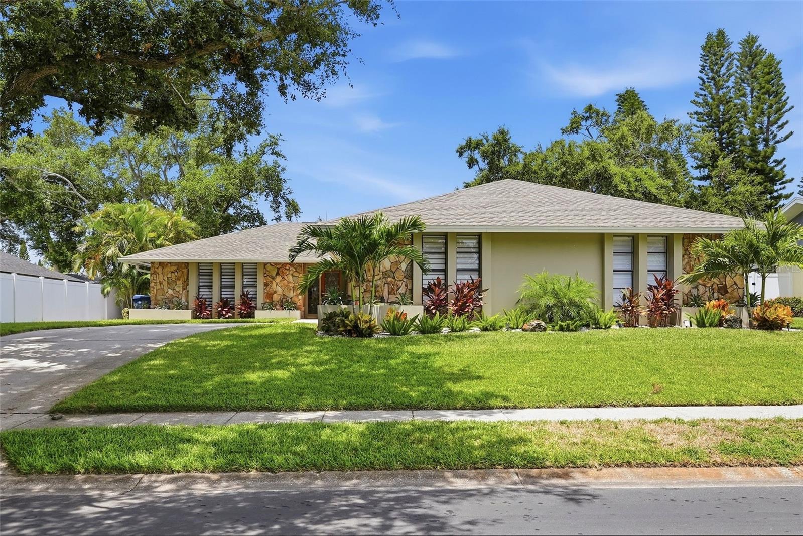 Welcome to The Bluffs, presenting this beautifully updated 4-bedroom, 3-bathroom pool home perfectly blends timeless style, everyday comfort, and an exceptional location. Just five minutes from Belleair Beach, premier dining, and shopping, this solid block home is situated in a NON-FLOOD ZONE, offering both peace of mind and convenience. Step inside to discover a bright, open-concept floor plan with a desirable split-bedroom layout, designed for both privacy and effortless living. Gorgeous porcelain tile flooring extends throughout the home, creating a seamless, carpet-free interior. At the heart of the home, the thoughtfully designed chef's kitchen features quartz countertops, solid wood cabinetry, and an ideal layout that flows effortlessly into both formal and casual dining spaces. The spacious primary suite is a true retreat, complete with a walk-in closet, private sliders leading directly to the pool, and a beautifully appointed ensuite bath featuring dual vanities and a walk-in shower. Designed for entertaining, expansive sliding glass doors in both the kitchen and living area create a seamless transition to your own private outdoor oasis. Enjoy a freshly resurfaced saltwater pool enclosed by a screened lanai, surrounded by lush tropical landscaping, ambient outdoor lighting, and a charming flagstone patio with a propane fire pit—perfect for relaxing evenings or gathering with family and friends. Additional highlights include a newly installed A/C unit, a dedicated laundry room with new cabinetry, vinyl privacy fencing, a sprinkler system with updated mechanicals, providing comfort and peace of mind for years to come. Offering the very best of Florida living in an unbeatable location, this exceptional home is ready to welcome its next owner.