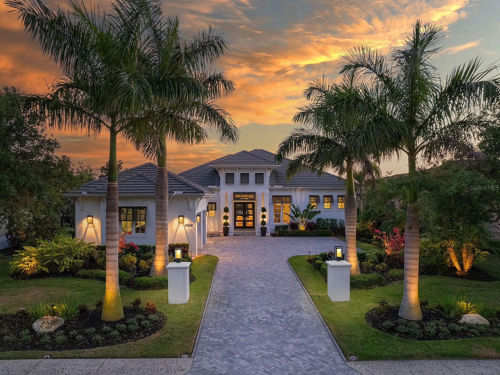 The ultimate in upscale, lakefront living could be yours in one of the most desirable neighborhoods in the exclusive Lake Club! This one-of-a-kind custom built 2017 Todd Johnston home has been meticulously updated throughout 2020 to 2024 to reflect modern living – you won’t find another home like this in all of Lakewood Ranch. You’ll be welcomed home to your new Florida paradise from the herringbone paver driveway, past 2022 landscaping including towering Royal Palms with lighting to the grand front entry with double iron and glass front doors. Inside the impeccable design choices are certain to please the most discerning tastes including amazingly high ceilings reaching up to 16', cove crown molding, French oak wood flooring, transom windows for additional light, built-in ceiling speakers, and custom designer window treatments and light fixtures. The central great room is the heart of the home with custom feature wall with fireplace and glass display shelving, 16' coffered ceiling, 2022 Restoration Hardware 7-tier chandelier, and 10’ pocketing impact sliding glass doors to the lanai. Offering over 80’ of lakefront, the shellstone paver lanai is surrounded by Clear View screening and colonnade for unparalleled views, plus the heated saltwater pool and spa are perfectly positioned to enjoy the peaceful view. Relax on the lanai under two spacious covered entertaining areas with 2022 wood ceilings and ceiling fans, 2022 built-in gas firepit bowl and 2021 upgraded outdoor kitchen including stainless steel grill, bar fridge, wine fridge, separate burner, and counter-to-ceiling tile backsplash. For a seamless indoor-outdoor experience, the formal dining room has disappearing corner impact sliders for an open flow between the kitchen and dining spaces. The formal dining also includes a 2022 designer chandelier and built-in dry bar buffet with Taj Mahal quartzite counters. The executive kitchen will have you cooking in luxury amongst a Jenn-Aire stainless steel appliance suite, 2021 KitchenAid built-in refrigerator, central island with seating, Taj Mahal quartzite counters and full-height backsplash, plentiful storage, display cabinetry, and a walk-in closet with custom shelving. Take in more lake views from the rear bonus room also with impact sliding glass doors to the lanai and featuring a 2021 dry bar with Zepyhr wine refrigerator, KitchenAid dual drawer refrigerators, and Scotsman ice maker amid quartz counters. Your private retreat is found in the primary suite with vestibule entry, seating area with chandelier, and dual walk-in closets with custom built-in shelving. Take relaxation to the next level in the spa-like primary bathroom with a large freestanding modern tub, dual sinks on split vanities with tower storage, and roman-style walk-in shower with frameless glass enclosure, dual shower heads and built-in benches. The floor plan has been reworked to now offer a brand new 2021 powder bathroom and ensure both guest bedrooms have their own private en-suite bathrooms with the same luxurious upgrades as the rest of the house. Complementing this residence is an open study with chandelier, laundry room with cabinetry, hall with added closets/storage and 3-car sideloading garage with 2023 cabinetry. The Lake Club is a premier, private gated community including a Grande Clubhouse, restaurant, pool, tennis, pickleball, playground, basketball, Linear Park, fitness center, dog park and interlinking lakes for kayaking or fishing.