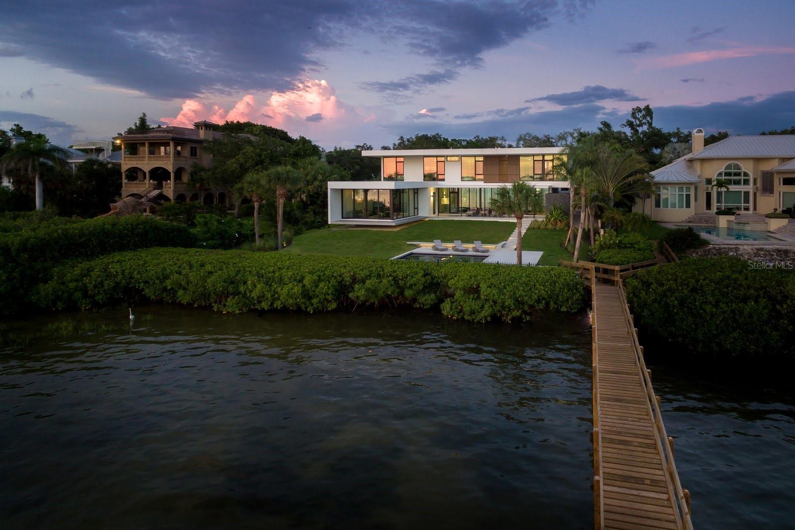 Nestled in the heart of Sarasota, Florida, "The Seathrough House" stands as a testament to timeless elegance and modern sophistication. Designed by the acclaimed architectural firm Sweet Sparkman and meticulously crafted by builder Josh Wynne, this mid-century marvel redefines luxury living. From the moment you step inside, the panoramic bay views captivate the senses, seamlessly blending the indoors with the breathtaking natural beauty of the surroundings. Every room boasts expansive windows, offering an uninterrupted vista of Sarasota Bay that is nothing short of mesmerizing. This architectural masterpiece features five bedrooms and five baths, providing ample space for both relaxation and entertaining. Each room is thoughtfully designed to maximize comfort and functionality while showcasing the stunning waterfront backdrop. Situated "West of the Trail," this premier location places you just minutes away from the world-renowned Siesta Beach, downtown Sarasota, and the charming Southside Village. Whether you're strolling along the pristine shores of Siesta Key or indulging in the vibrant cultural scene of downtown, every convenience is within easy reach. For those who appreciate the finer things in life, "The Seathrough" house offers more than just luxurious living—it promises a lifestyle of unparalleled elegance and sophistication. With a shared dock featuring a 16,000 lb lift, residents can effortlessly explore the azure waters of the Gulf Coast or simply bask in the warmth of the Florida sun as they watch the gorgeous sunsets from the home or the bayfront poolpaint the sky in hues of orange and gold. "The Seathrough" house is not just a home—it's a sanctuary where every moment is infused with beauty, tranquility, and the unmistakable charm of Sarasota living at its finest.