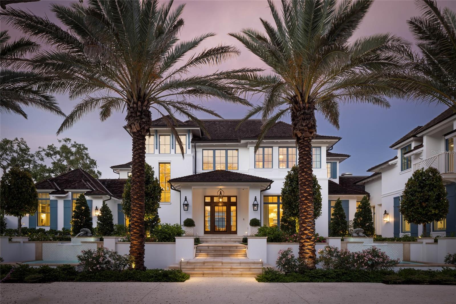 Set across nearly three acres of pristine waterfront on Siesta Key, Crystal Waters is the most significant private estate in Sarasota—a once-in-a-generation offering that redefines luxury living on Florida’s Gulf Coast. With extraordinary scale, architectural pedigree, and 217 feet of direct Sarasota Bay frontage, this landmark property represents a level of craftsmanship, beauty, and exclusivity rarely seen in the region.
Designed by renowned architectural firm Stofft Cooney Architects and custom-built by Chris Jorgensen of Florida West Builders, the Palm Beach-inspired estate encompasses 10,267 square feet with five bedrooms, six full baths, and two half baths. Surrounded by lush tropical gardens and panoramic bay views, every aspect of the property has been conceived to deliver an unparalleled waterfront lifestyle.
A dual-gated arrival along a Tabby seashell drive leads to a stately façade framed by towering palms and a grand porte cochère. Beyond solid mahogany doors, a magnificent foyer welcomes guests with travertine floors inlaid with cabochon stone and a sweeping staircase featuring hand-crafted Chippendale railings. Walls of impact glass dissolve the boundary between indoors and out, filling the residence with natural light and uninterrupted views of Sarasota Bay. Refined details include a natural gas fireplace with imported limestone hearth, hand-crafted Vitali European oak flooring in a warm Milano finish, custom millwork, and a serene palette of coastal hues. The kitchen is both a showpiece and gathering place, appointed with custom Campbell cabinetry, Cristallo quartzite surfaces, a custom La Cornue range, dual islands, and walk-in and butler’s pantries. A bayfront breakfast nook and formal dining room open seamlessly to expansive waterfront terraces. Nearby, the clubroom showcases hand-painted Gracie chinoiserie panels, vaulted cypress ceilings, and a wet bar. The first-floor primary suite serves as a private sanctuary overlooking the bay, with French doors opening to the pool terrace. Custom dressing rooms and spa-inspired baths surround a striking octagonal vestibule featuring New Ravenna mosaic floors, Calacatta Matarazzo quartzite, a soaking tub, and marble-clad shower. Upstairs, guest suites, a lounge, and an exercise room provide exceptional accommodations. An Old Florida-style guest residence above a four-car garage offers Pecky Cypress-lined interiors, vaulted ceilings, a full kitchen, covered balcony, and spacious bedroom suite. The main residence is further complemented by an oversized three-car garage. Outdoors, winding pathways lead through beautifully curated grounds to a spectacular 56-foot vanishing-edge saltwater pool that appears to merge with the bay beyond. A covered waterfront pavilion with fireplace, summer kitchen, and tongue-and-groove ceiling creates an elegant setting for entertaining. A private tennis court and lighted pavilion with lounge and fireplace complete the resort-caliber amenities. Along the shoreline, a 90-foot dock extends into Little Sarasota Bay and features a floating kayak launch and a 20,000-pound lift capable of accommodating a 34-foot vessel. Crystal Waters is more than a residence—it is Sarasota’s defining waterfront estate. Unmatched in scale, setting, craftsmanship, and provenance, it stands as one of the finest private properties ever created on Florida’s Gulf Coast. Available lot for sale directly across the street enjoys beach access.