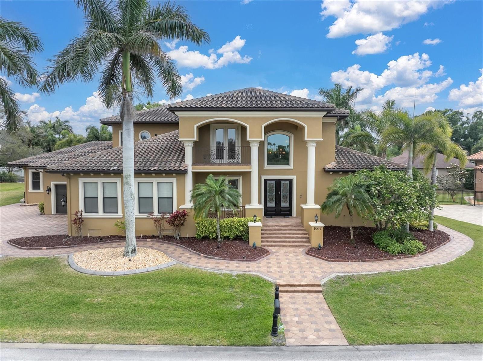 Welcome to 1067 Ashland Ave, a sophisticated Tarpon Springs residence offering over 5,800 square feet of refined living just minutes from Sunset Beach. Designed for both elegance and resilience, this custom home features 4 bedrooms, 6 bathrooms, a 3-car garage, dual lanais, a resort-style pool, Wolf/Sub-Zero kitchen, Tesla backup power, 40 solar panels that reduce monthly electric costs by more than 80%, and a private in-law suite with its own entrance.

The heart of the home is the chef’s kitchen, equipped with Wolf appliances, Sub-Zero refrigeration, custom cabinetry, and an oversized island that flows seamlessly into expansive living and dining spaces. Natural light fills the interior through large windows and sliders, creating a warm, inviting atmosphere.

The primary suite is a private retreat with generous proportions, a spa-inspired bathroom, and custom storage. Three hurricane-rated safe rooms provide peace of mind, while dual Tesla Powerwall backups ensure uninterrupted comfort during storms.

Outdoor living is elevated with two separate lanais—one featuring a fireplace and retractable screens—overlooking a custom pool designed for relaxation and entertaining. Whether hosting gatherings or enjoying quiet evenings, these spaces offer year-round enjoyment.

A rare highlight is the in-law suite, complete with a private entrance, full bath, and living area—ideal for multigenerational living, guests, or extended stays.

Located in one of Tarpon Springs’ most desirable pockets, this home offers quick access to Sunset Beach, Fred Howard Park, the Sponge Docks, and the vibrant local dining scene. Luxury, comfort, and coastal living come together seamlessly at 1067 Ashland Ave. Shown by appointment.