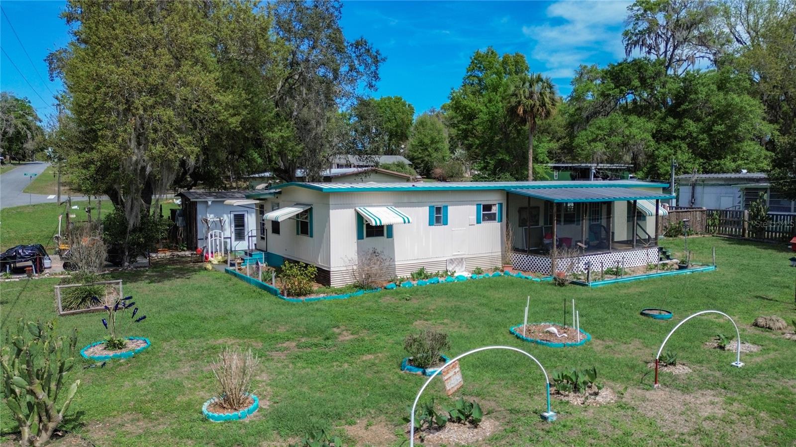 STOP THE CAR! If you've been looking for your next home with NO HOA, on over 1/4 of an acre, you just found it! And on a CORNER LOT for ultimate convenience and spaciousness! This 2 bedroom, 2 bathroom singlewide home has no shortage of living space, with an additional screened in lanai off one side of the home, and a climate controlled bonus room on the other side! The bedrooms in the home are split, with one bedroom at the front of the home, with an ensuite bathroom with walk-in shower, and the other bedroom at the opposite side of the home, with another full bathroom right next to it! The living space is completely open, with living room, dining space, and kitchen flowing together into one great room. The backyard is spacious and private, with a cypress board fence enclosing the yard. The white detached building would make a perfect guest house, or office, and includes a window AC unit and ceiling fan for climate control. Here you'll also find the washer / dryer hookups. There is an additional storage shed out back, and a new well house. If you're ready for peaceful country living, schedule your showing today!