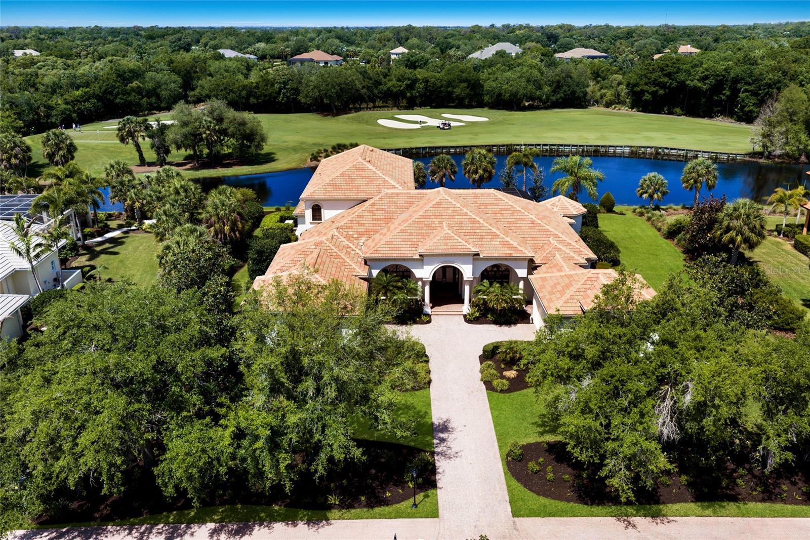 Sprawling 6,259 square foot estate on .76 acre in The Founders Club boasts breathtaking sunset golf and lake views over the third fairway in one of Sarasota’s premier lifestyle golf communities. Architecturally grand details are evident throughout this two-story residence with its generously-proportioned living spaces, volume coffered ceilings, built-in wood detailing, three gas fireplaces, accentuated by oversized windows and ten foot impact sliders to take in the breathtaking surrounding vistas.

The oversized lanai is anchored with travertine decking, gas fireplace, heated pool/spa and engulfed by the sublime views at every turn, while seamlessly connecting to the invitingly large living and great rooms open to the gourmet kitchen where form and function reigns cohesively. Chefs will delight with the custom wood cabinetry, sprawling granite counters, high performance appliances, wet bar with sink and fridge, butler pantry bar, built-in desk, walk-in pantry, walk-in hidden wine room with two wine fridges, and large breakfast nook area with built-in bench seating. The residence also features a magnificent club room adjoining the home's fifth full bath, offering an expansive retreat behind double doors complete with dry bar and refrigerator, direct lanai access, and sweeping golf and lake views.  

Relax and unwind in the oversized owner’s retreat on a private wing with its own sitting room, a gas fireplace, disappearing sliders open to the lanai, two walk-in customized closets, and an opulent  spa-like bath adorned with onyx and marble, a dual entry walk-in shower with multiple shower heads, bench seating, two vanity stations with abundant storage, make-up vanity, oversized jetted tub, and separate water closet with bidet. Family and overnight visitors will be right at home with 3 generously sized guest rooms all outfitted as large suites with private full baths and walk-in closets, one on the main level, and two on the upper level with direct veranda access. Upstairs is  also large theater room designed for cinema seating.  

Other notable highlights of this all-encompassing four-bedroom suite residence includes a private Office with built-ins and plantation shutters, a separate Powder Room conveniently located, a laundry room with sink, cabinetry and storage closet, solid interior doors, central vacuum, newer water heater, 4 AC units aged between 2020 and 2022, landscape lighting, GENERATOR, paver driveway, and a split 4-car courtyard garage with newly replaced operating mechanisms. 

This one-of-a-kind masterpiece is a testament to refined living in the Founders Club  with over 700 acres of natural beauty offering low density living with 262 homesites, a Robert Trent Jones, Jr. designed 18 hole championship golf course, tennis courts, fitness center, miles of brick pavered walking paths, and fabulous 24,000 square foot clubhouse with a full calendar of events, positioned conveniently with easy access to Lakewood Ranch’s Waterside Place and Sarasota's downtown, beaches, shopping, dining and medical centers.