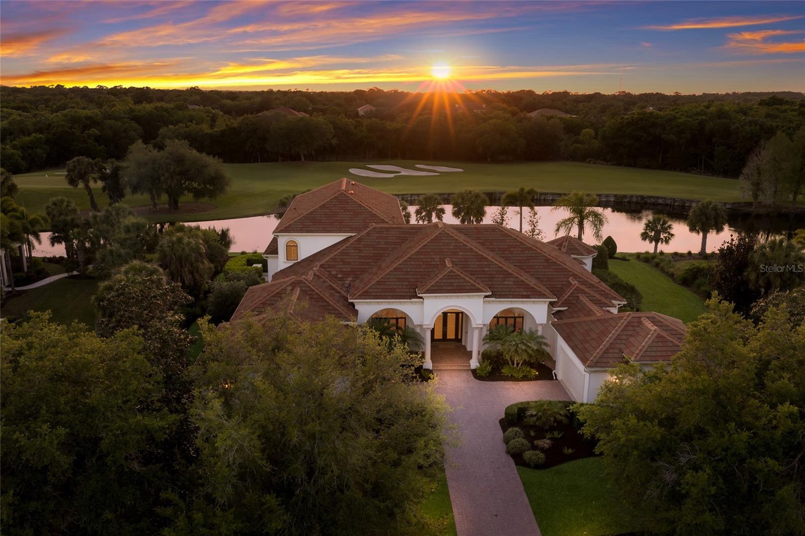 Sprawling 6,259 square foot estate on .76 acre in The Founders Club boasts breathtaking sunset golf and lake views over the third fairway in one of Sarasota’s premier lifestyle golf communities. Architecturally grand details are evident throughout this two-story residence with its generously-proportioned living spaces, volume coffered ceilings, built-in wood detailing, three gas fireplaces, accentuated by oversized windows and ten foot impact sliders to take in the breathtaking surrounding vistas.

The oversized lanai is anchored with travertine decking, gas fireplace, heated pool/spa and engulfed by the sublime views at every turn, while seamlessly connecting to the invitingly large living and great rooms open to the gourmet kitchen where form and function reigns cohesively. Chefs will delight with the custom wood cabinetry, sprawling granite counters, high performance appliances, wet bar with sink and fridge, butler pantry bar, built-in desk, walk-in pantry, walk-in hidden wine room with two wine fridges, and large breakfast nook area with built-in bench seating. The residence also features a magnificent club room adjoining the home's fifth full bath, offering an expansive retreat behind double doors complete with dry bar and refrigerator, direct lanai access, and sweeping golf and lake views.  

Relax and unwind in the oversized owner’s retreat on a private wing with its own sitting room, a gas fireplace, disappearing sliders open to the lanai, two walk-in customized closets, and an opulent  spa-like bath adorned with onyx and marble, a dual entry walk-in shower with multiple shower heads, bench seating, two vanity stations with abundant storage, make-up vanity, oversized jetted tub, and separate water closet with bidet. Family and overnight visitors will be right at home with 3 generously sized guest rooms all outfitted as large suites with private full baths and walk-in closets, one on the main level, and two on the upper level with direct veranda access. Upstairs is  also large theater room designed for cinema seating.  

Other notable highlights of this all-encompassing four-bedroom suite residence includes a private Office with built-ins and plantation shutters, a separate Powder Room conveniently located, a laundry room with sink, cabinetry and storage closet, solid interior doors, central vacuum, newer water heater, 4 AC units aged between 2020 and 2022, landscape lighting, GENERATOR, paver driveway, and a split 4-car courtyard garage with newly replaced operating mechanisms. 

This one-of-a-kind masterpiece is a testament to refined living in the Founders Club  with over 700 acres of natural beauty offering low density living with 262 homesites, a Robert Trent Jones, Jr. designed 18 hole championship golf course, tennis courts, fitness center, miles of brick pavered walking paths, and fabulous 24,000 square foot clubhouse with a full calendar of events, positioned conveniently with easy access to Lakewood Ranch’s Waterside Place and Sarasota's downtown, beaches, shopping, dining and medical centers.